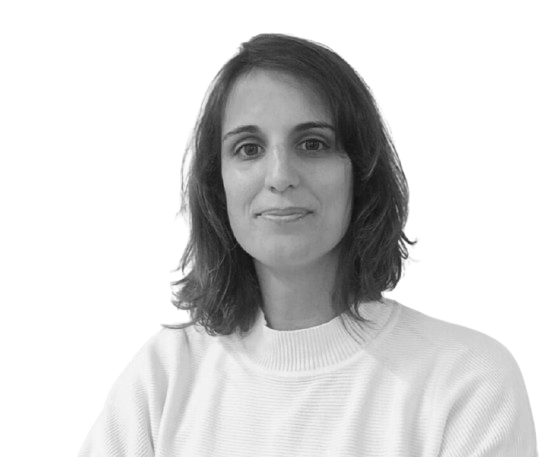 Retrato de uma mulher com cabelo curto e bagunçado, sorrindo, usando suéter de gola alta em fundo claro