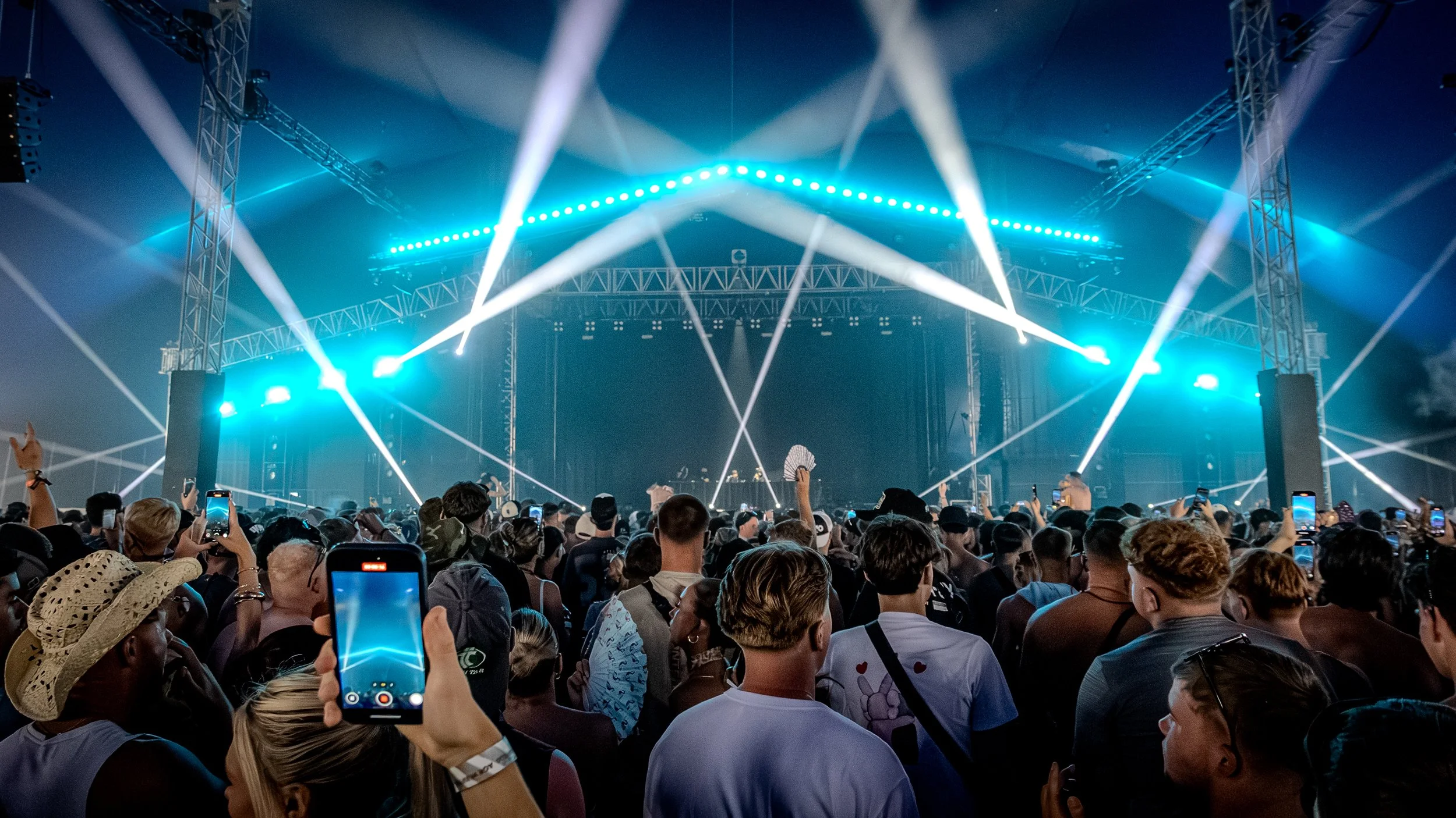 Crowd of people at a concert with stage lighting and laser effects