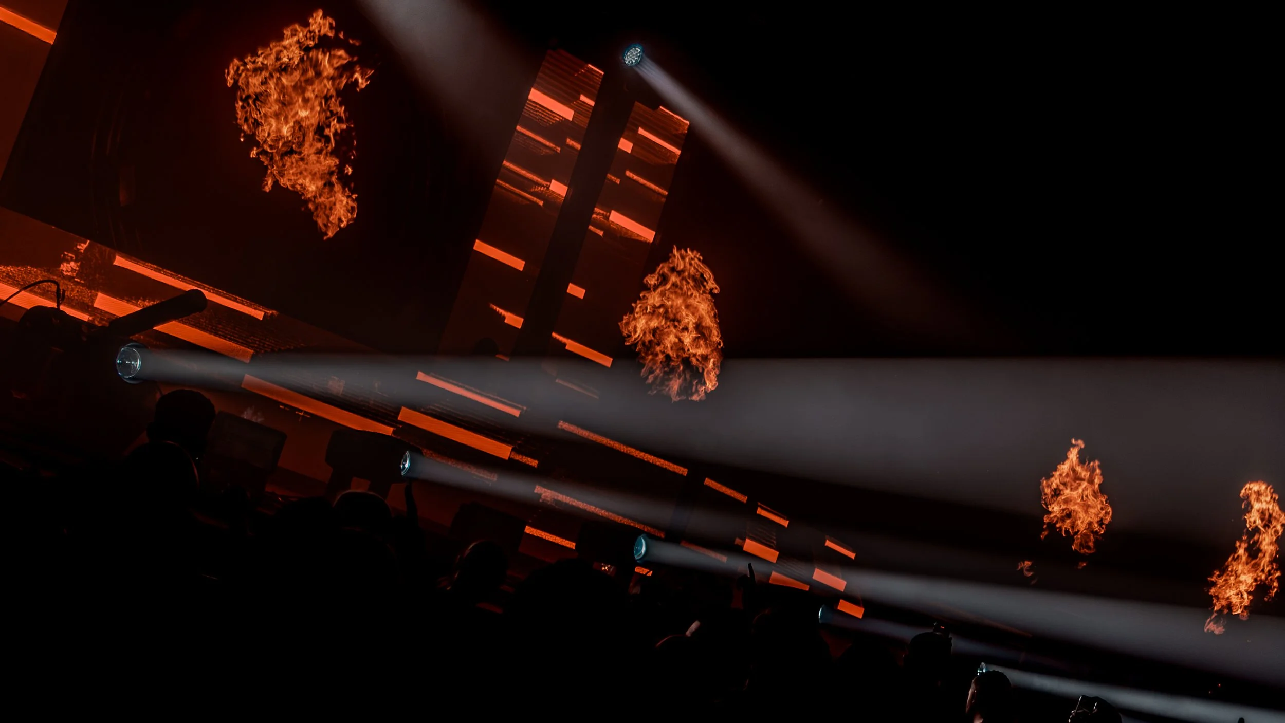 Stage with fire effects, flames rising from vents and spotlights illuminating the scene in red and orange hues.