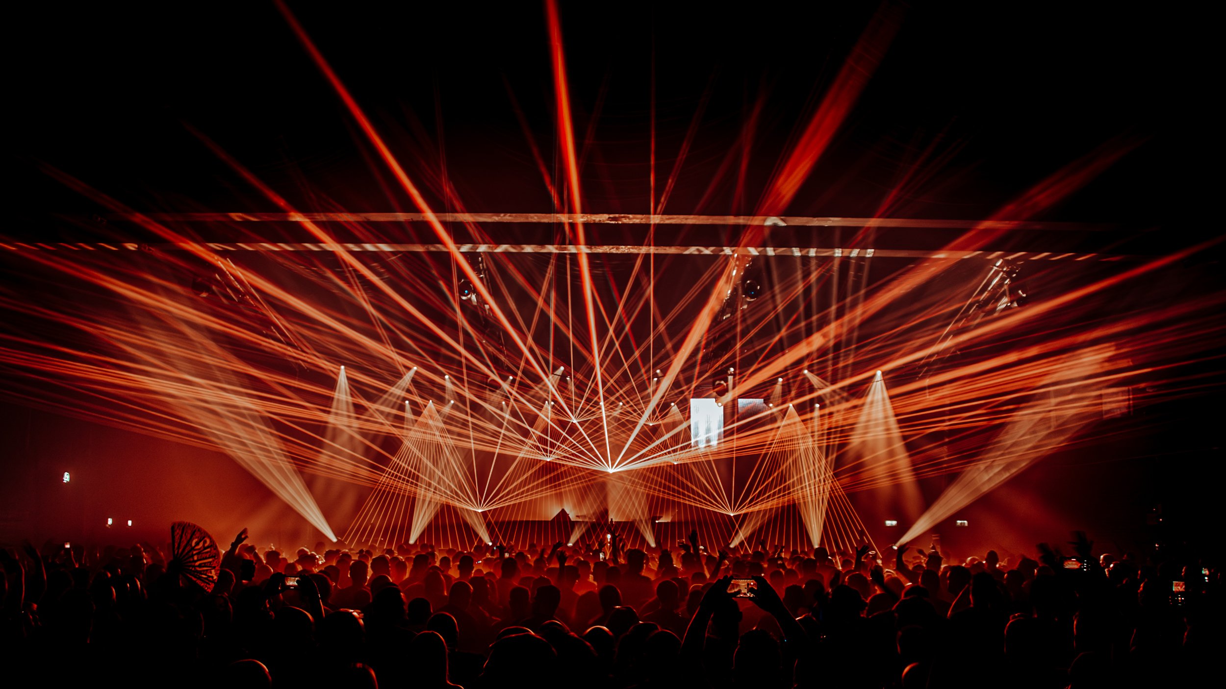 Concert with laser light show and audience silhouette at night.