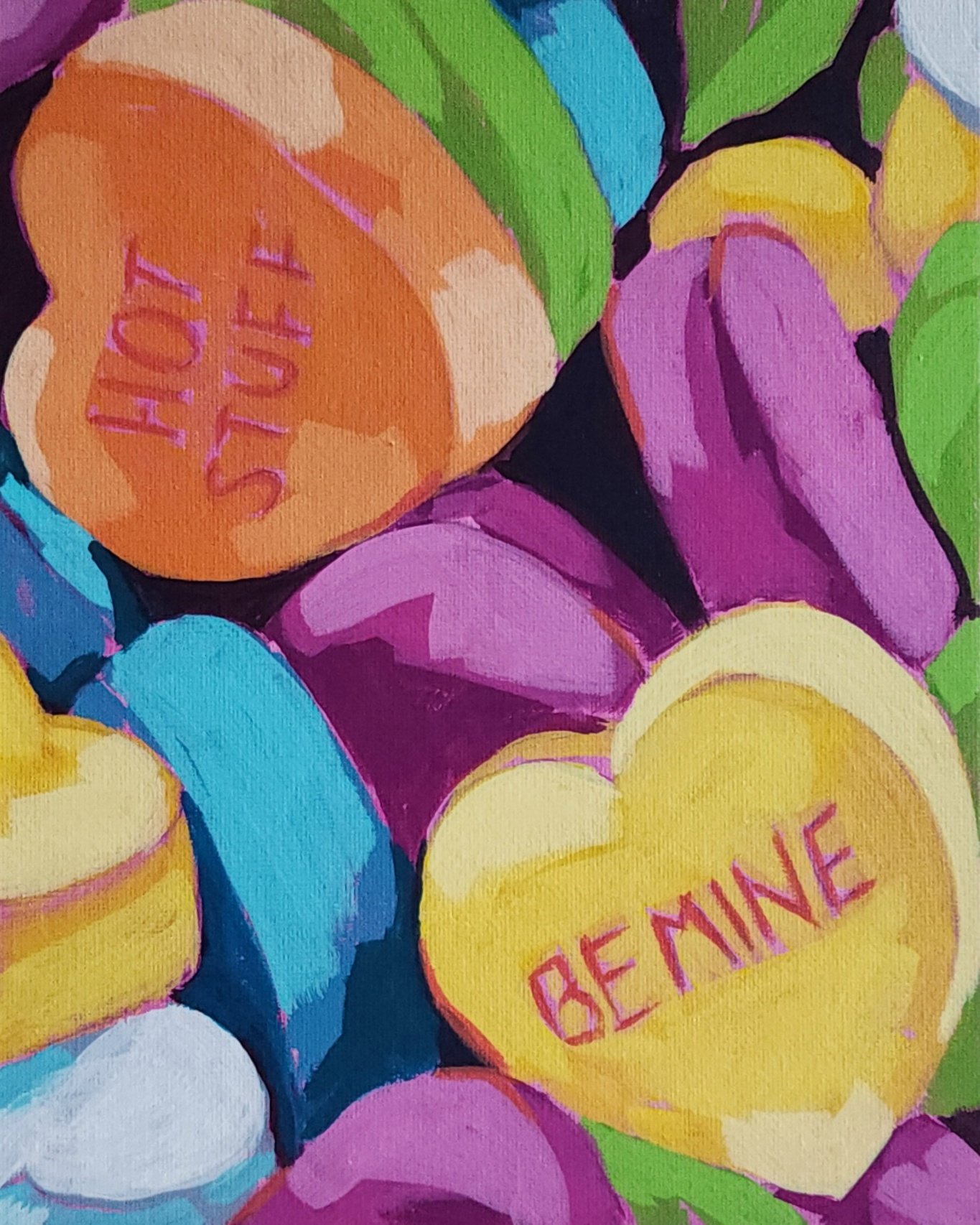 Brightly colored candy hearts with motivational words like "Hot Stuff" and "BE MINE" written on them, surrounded by other candy hearts.