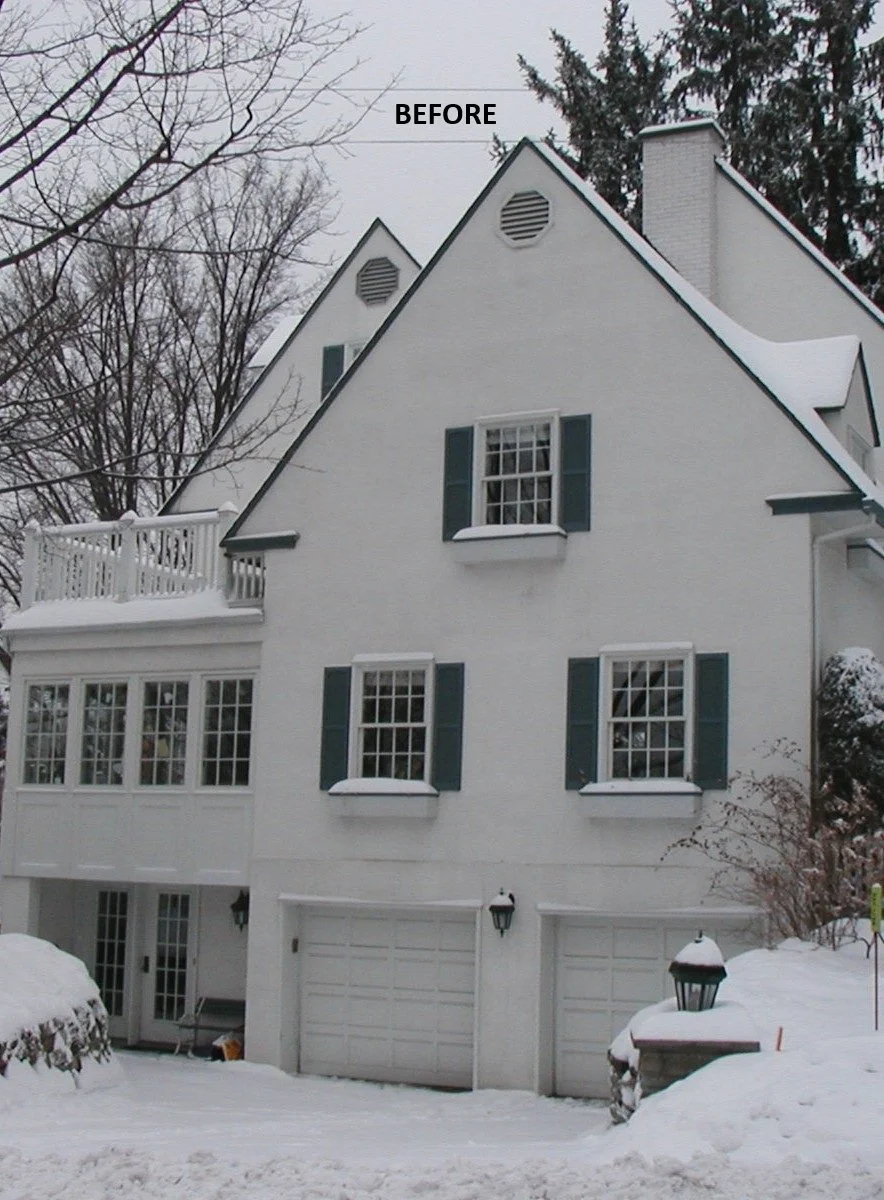 White multi-story house with dark shutters, three garage doors, and a snow-covered yard during winter.