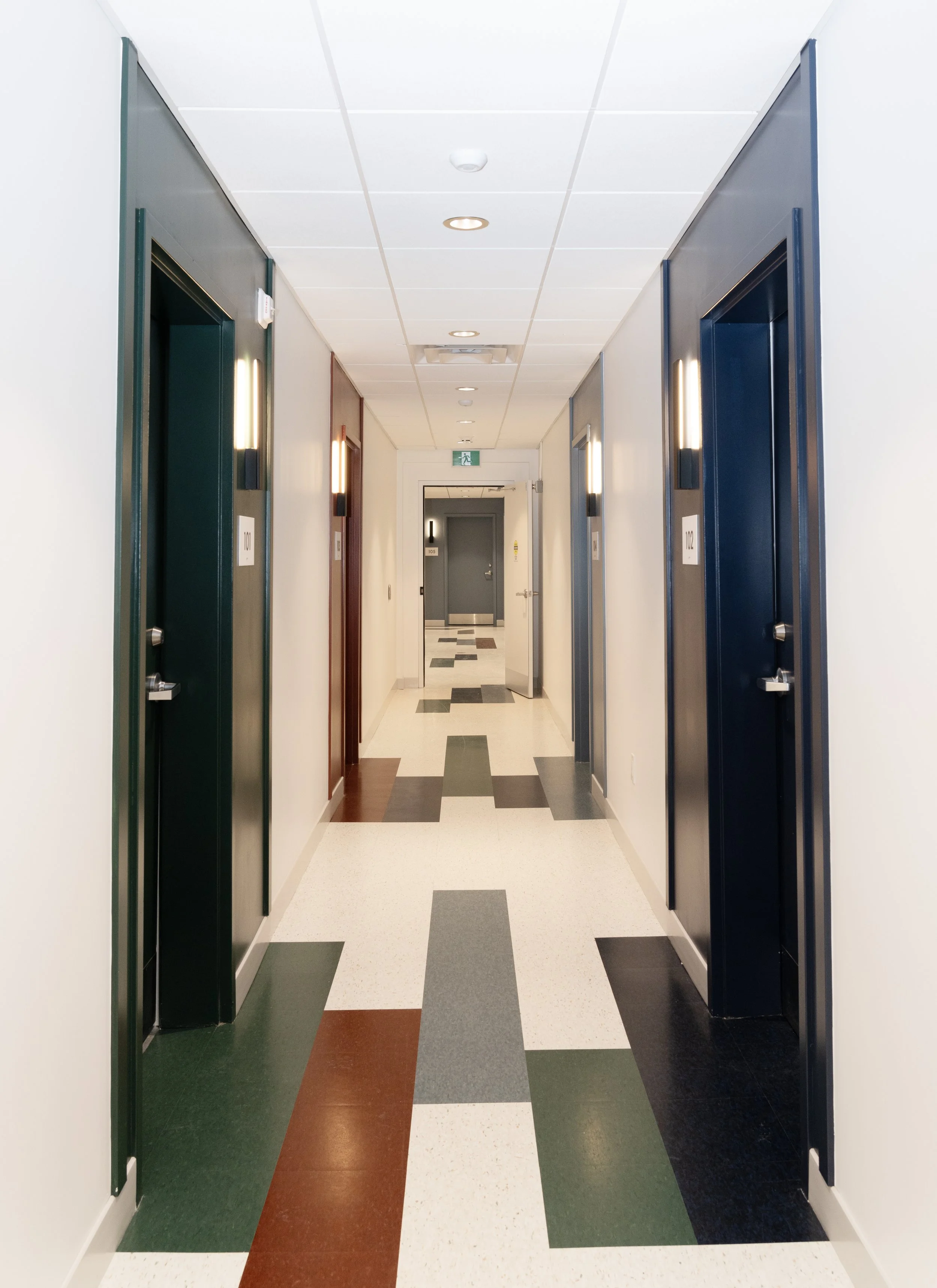 Clean hotel hallway with multiple elevator doors and a patterned tile floor.