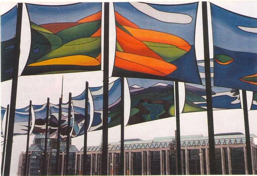 Colorful, abstract banners hanging above a city street with buildings in the background. NCC banner competition winner Jane Thompson, 1988 Ottawa Ontario Canada.