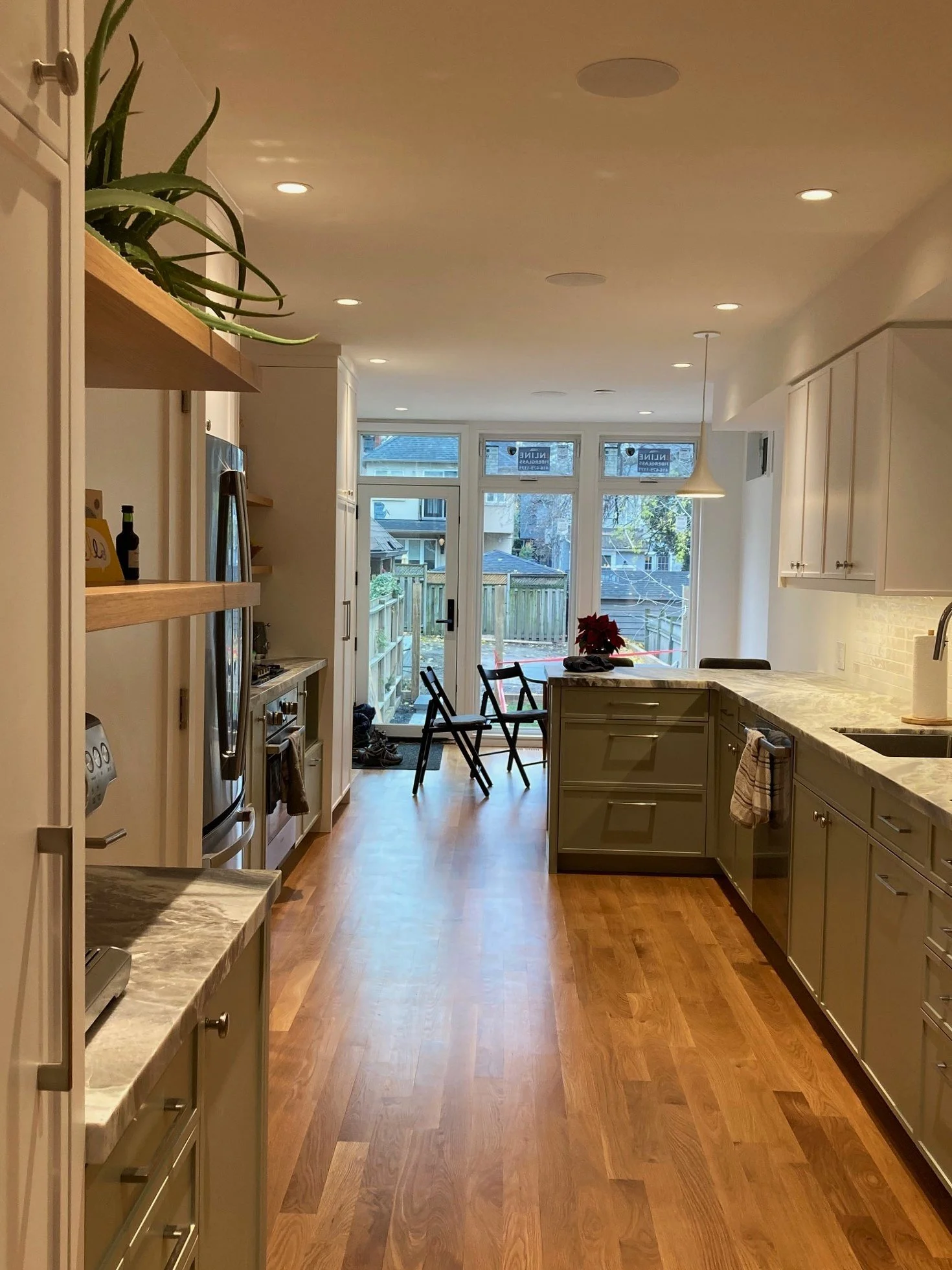 empty kitchen with light green cabinets, marble countertops, hardwood floor, a few chairs near large glass doors, and a small porch outdoor area.