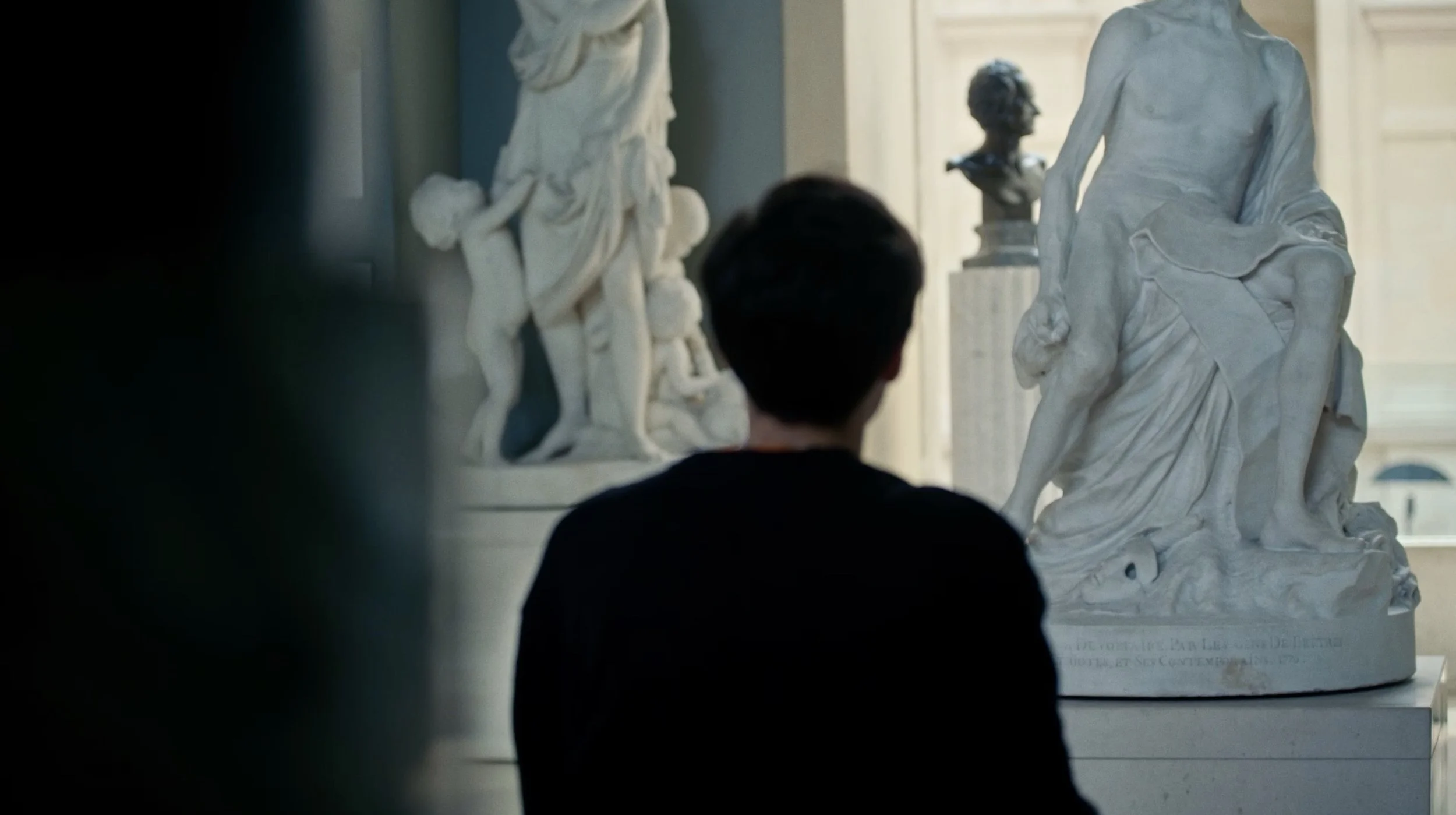 Une personne regarde une sculpture en marbre dans un musée.