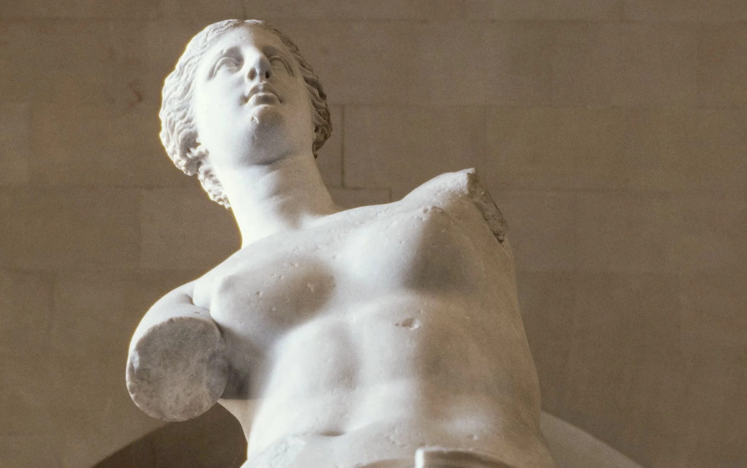 Sculpture en marbre représentant un homme nu vu de profil, avec une expression pensive, probablement un détail d'une statue antique