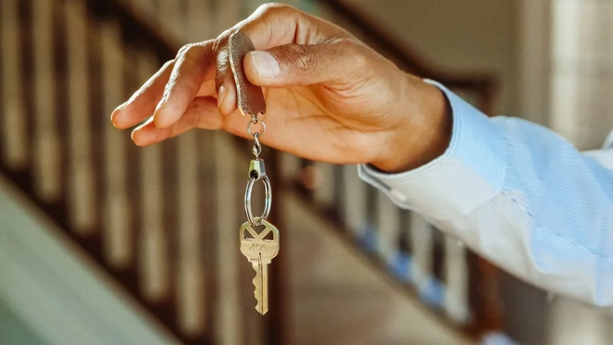 A hand holding the key to a rental property