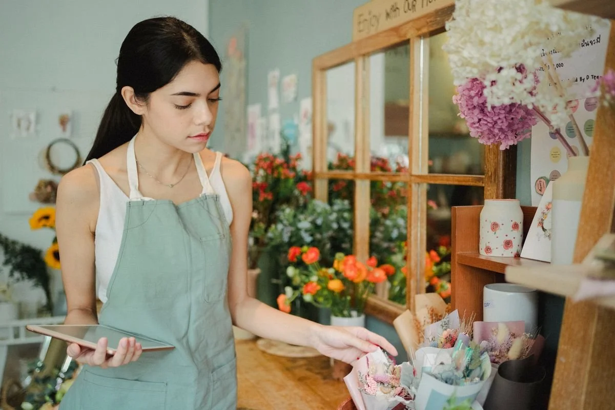 A florist checking orders on a tablet in her shop