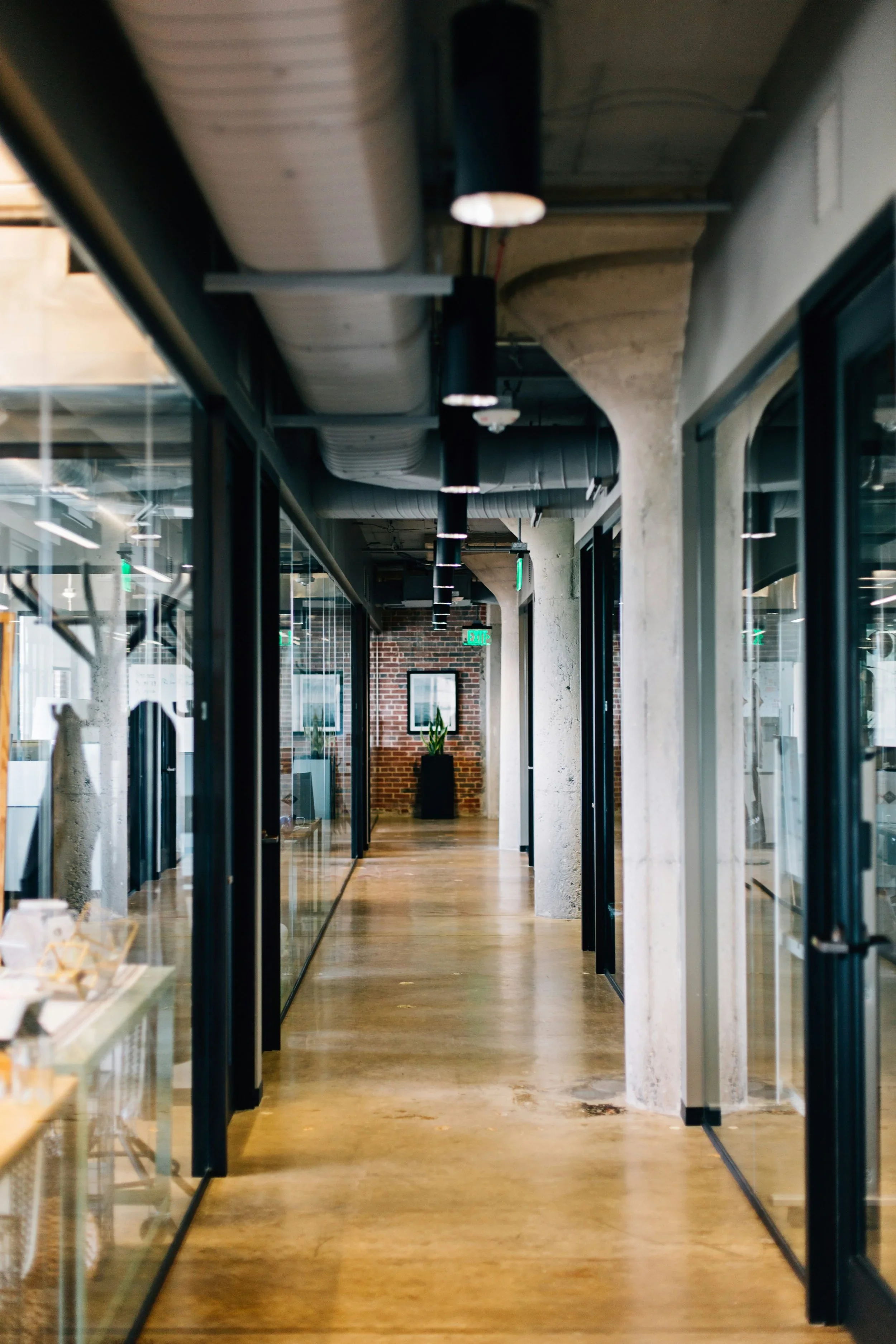 A modern office with glass walls and warm lighting.