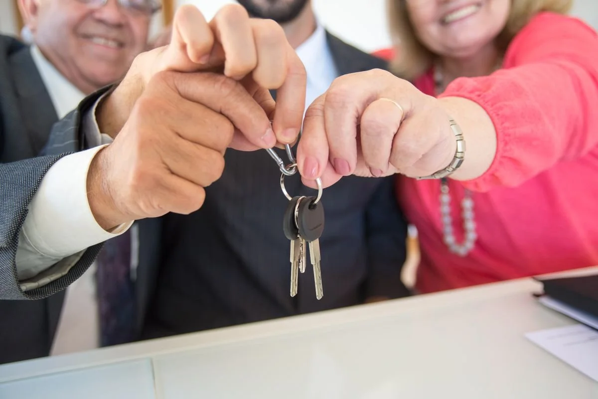 Clients and an agent exchanging keys after a property deal