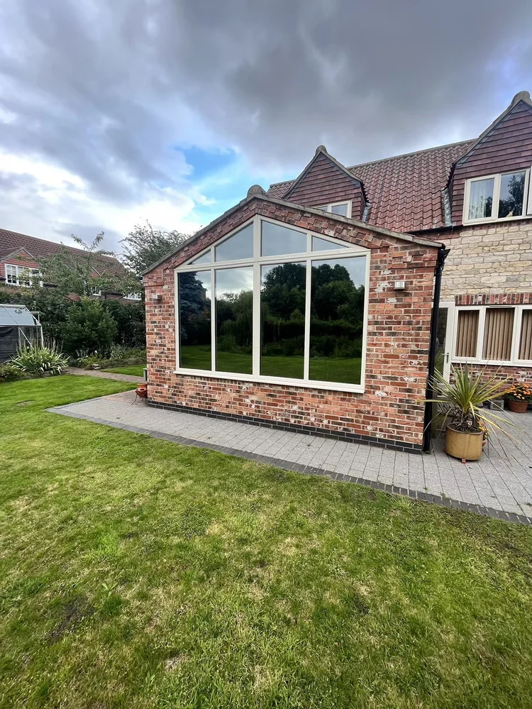 Brick house with a glass sunroom extension, film fitted