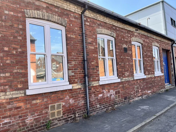 Brick building with four white-framed tinted windows