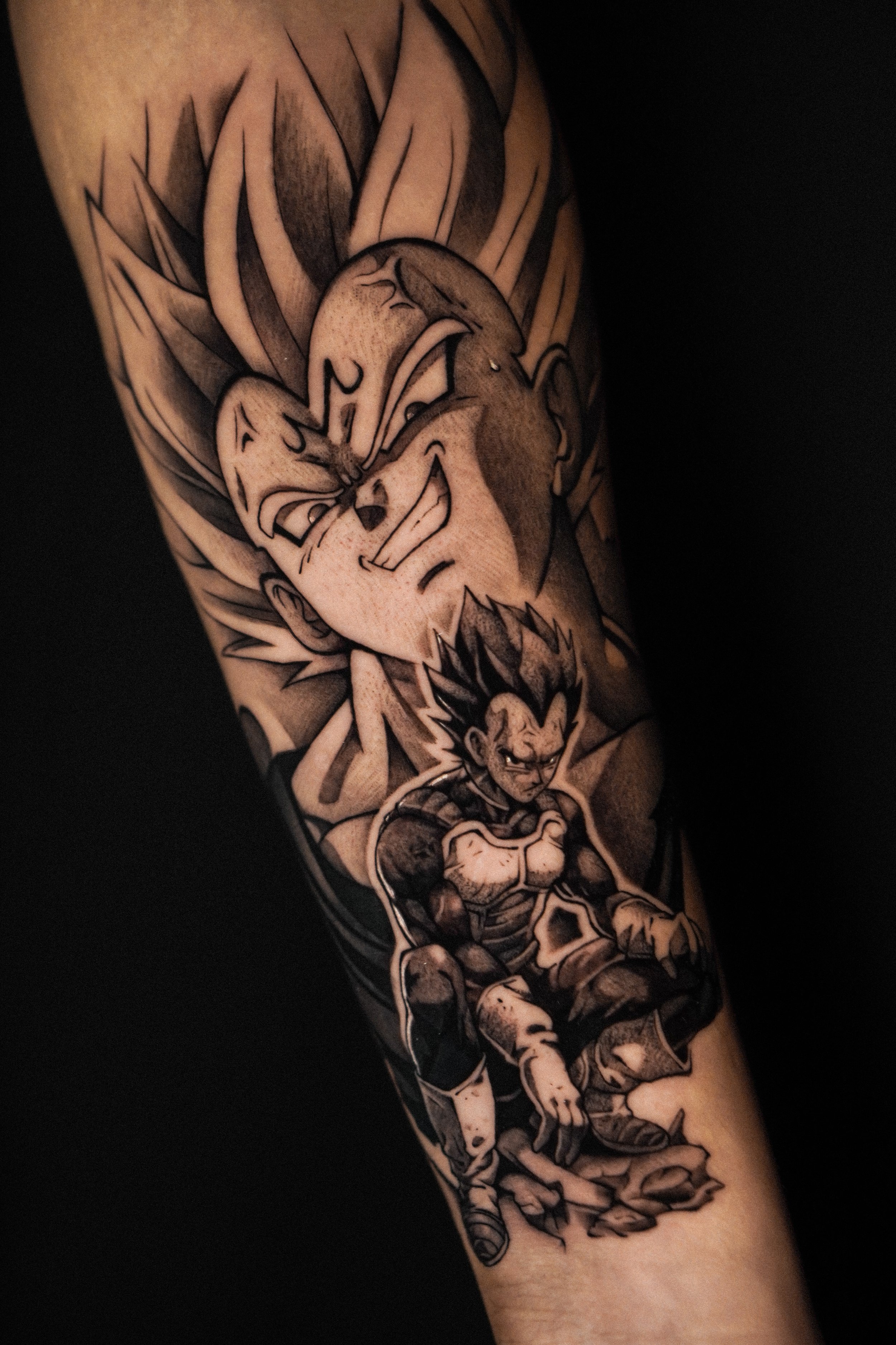 Tattoo featuring Dragon Ball characters in black and gray style, depicting a powerful scene on a person's arm.