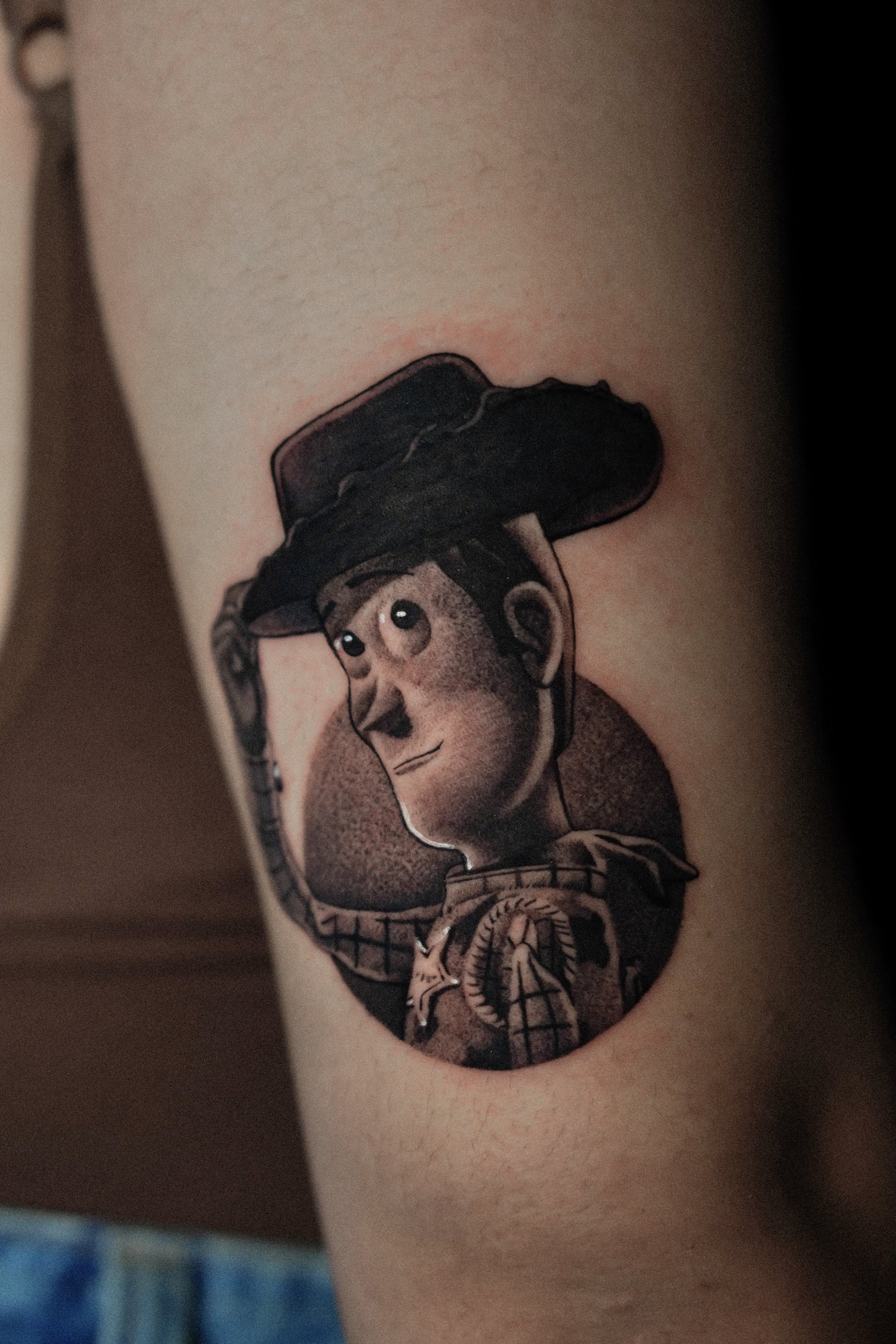 Tattoo of a cartoon cowboy character wearing a hat on a person's arm.