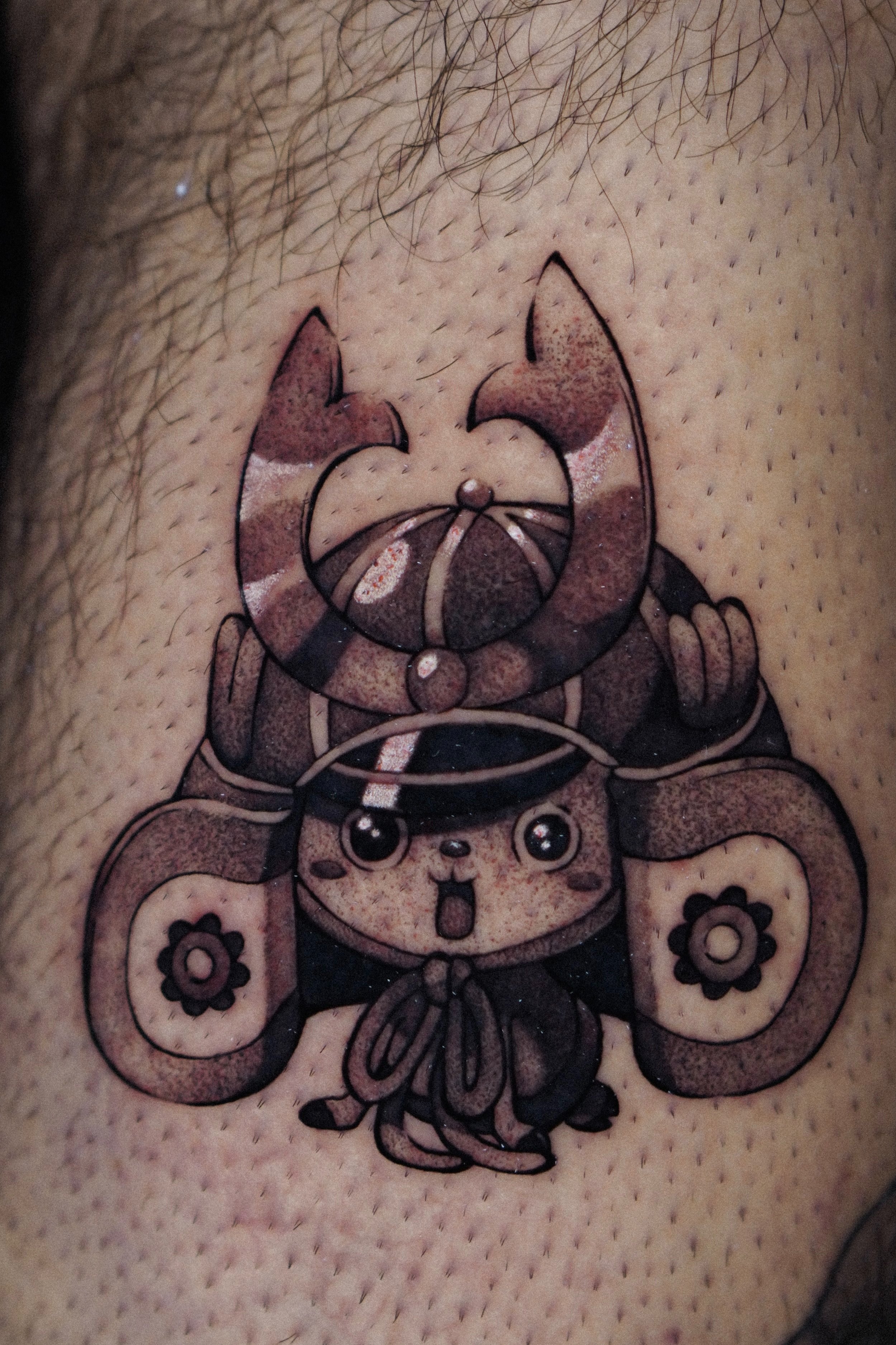 Tattoo of cartoon character wearing traditional Japanese samurai helmet on skin.