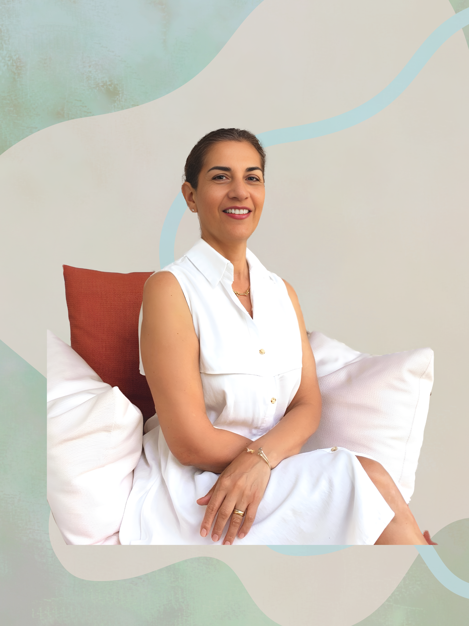Maggie Franco, Emotional Intelligence Coach, smiling while seated on a cushioned chair in a white dress, against a soft abstract background in green and beige tones.
