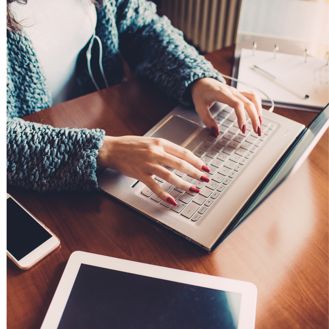 Woman typing on a laptop with a phone and tablet nearby, representing focused work and clear communication.