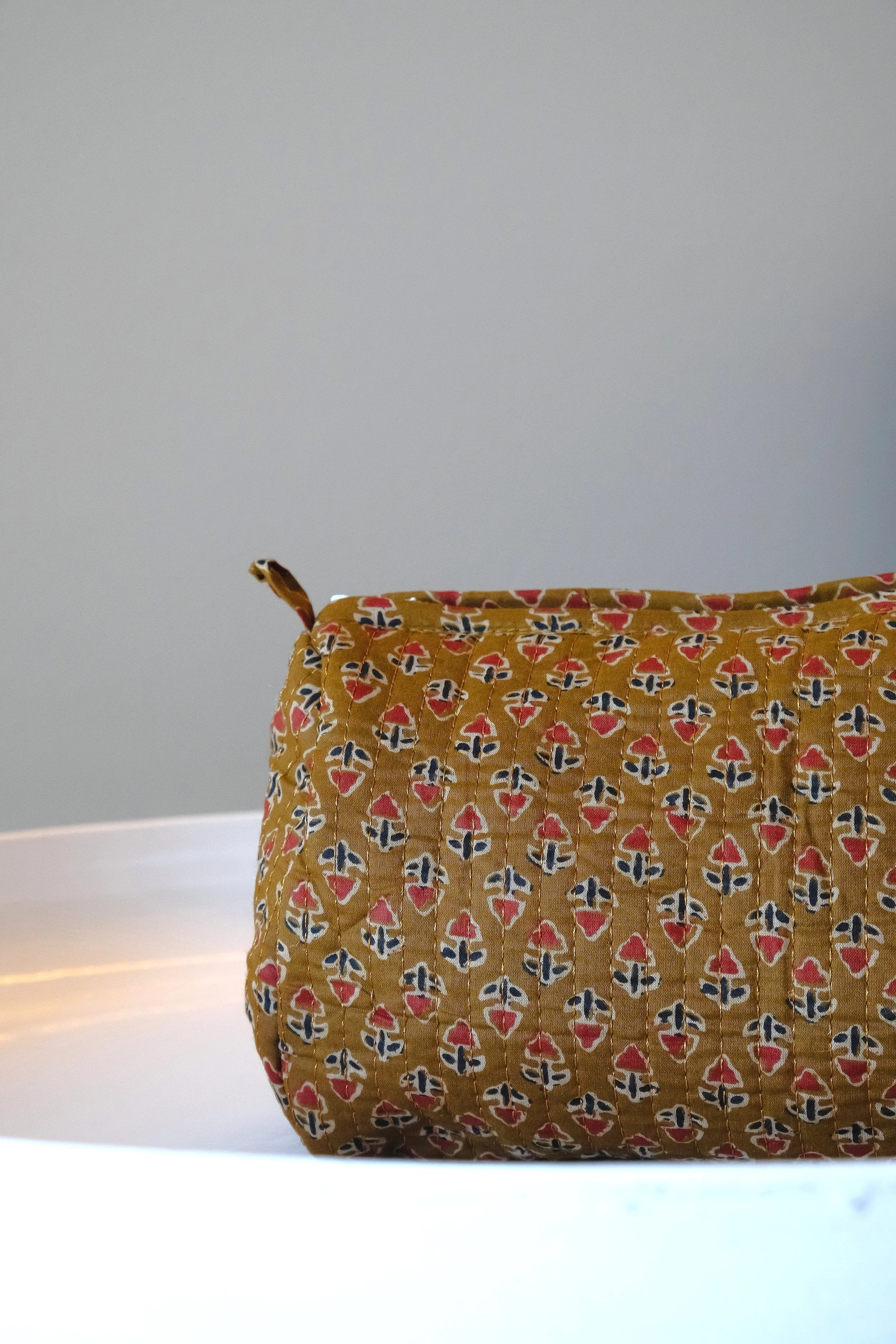 Bolsa con estampado de flores y formas geométricas sobre superficie blanca.