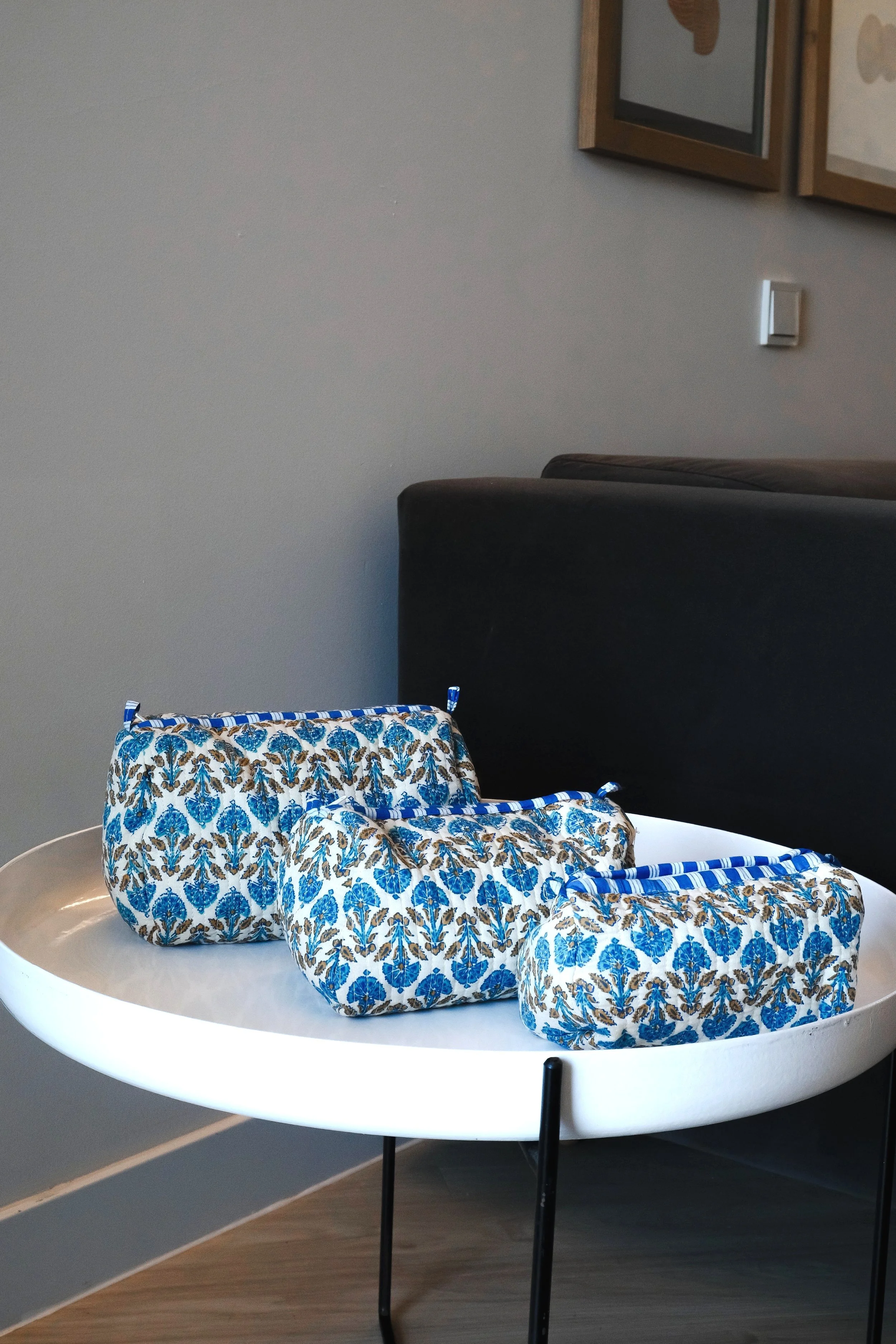 Tres bolsas de tela con estampado azul y marrón sobre una mesa blanca.