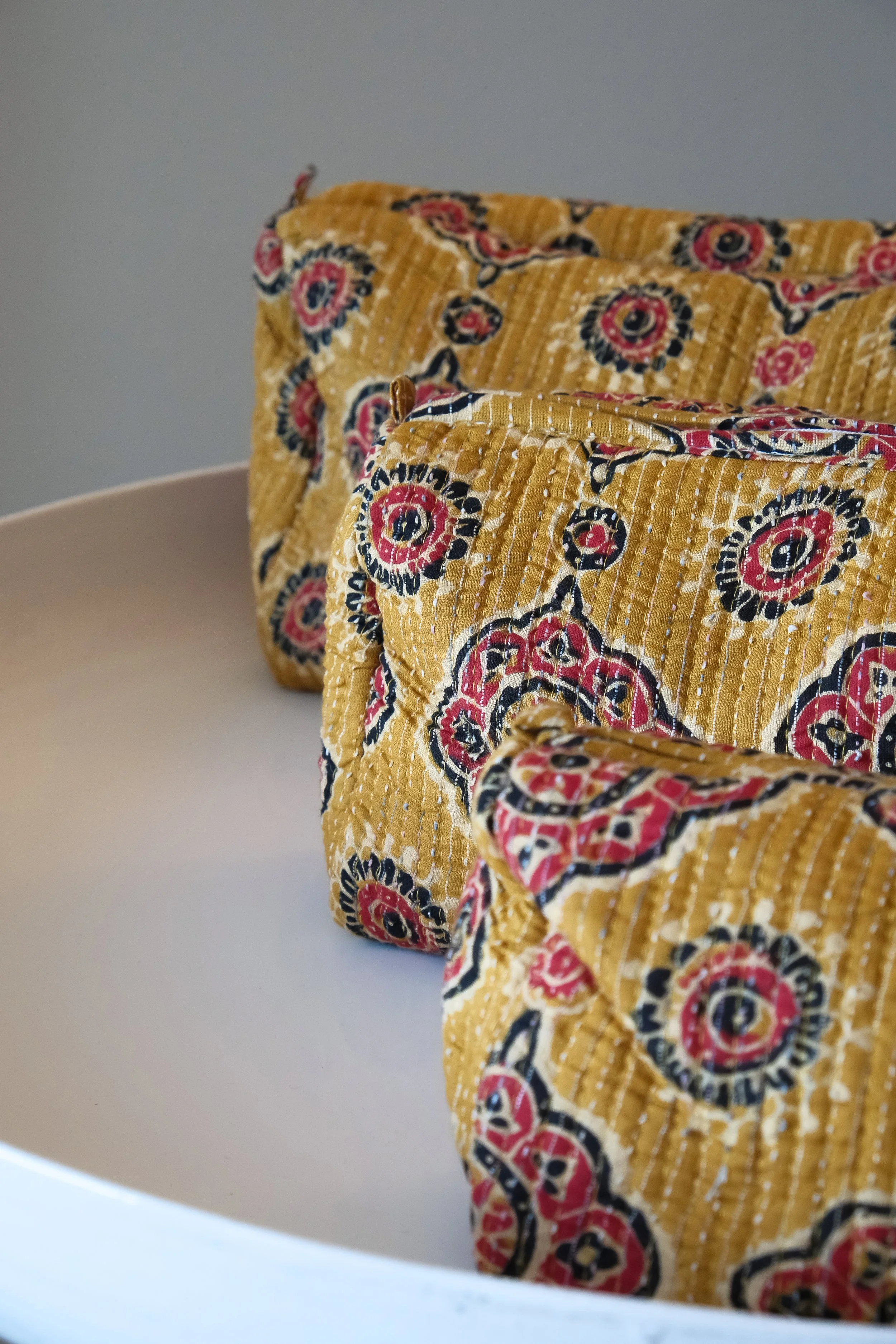 Estuches de tela amarilla con estampado floral en un plato blanco.