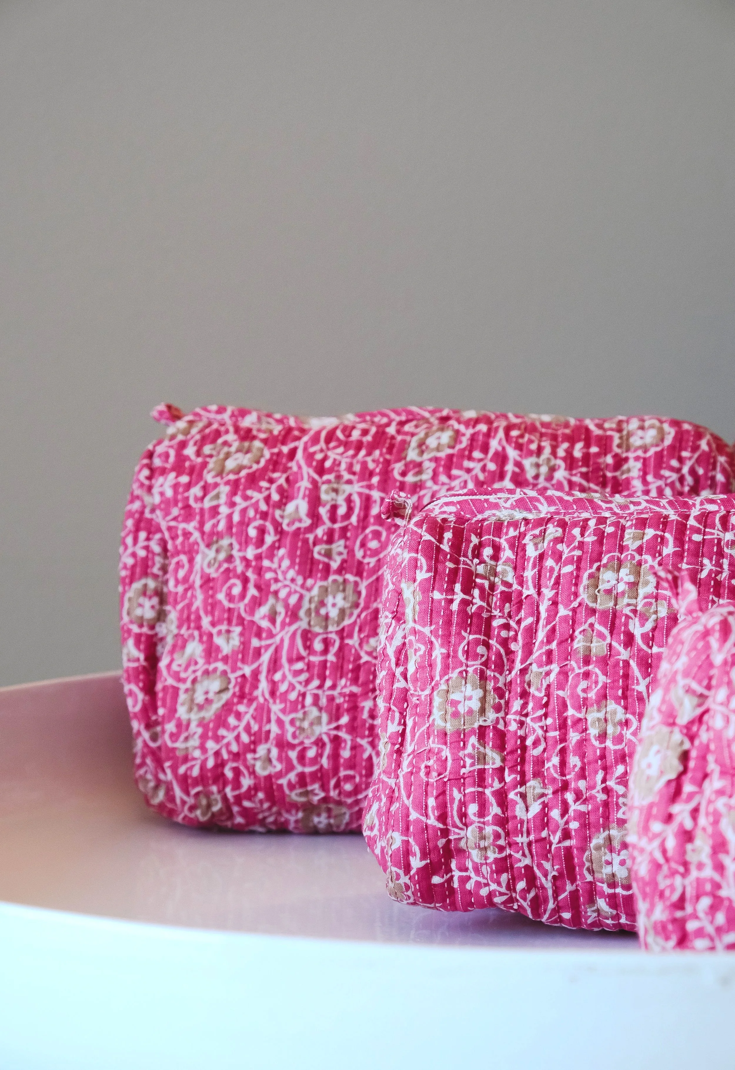 Dos cojines rosas con patrón floral sobre una superficie blanca.