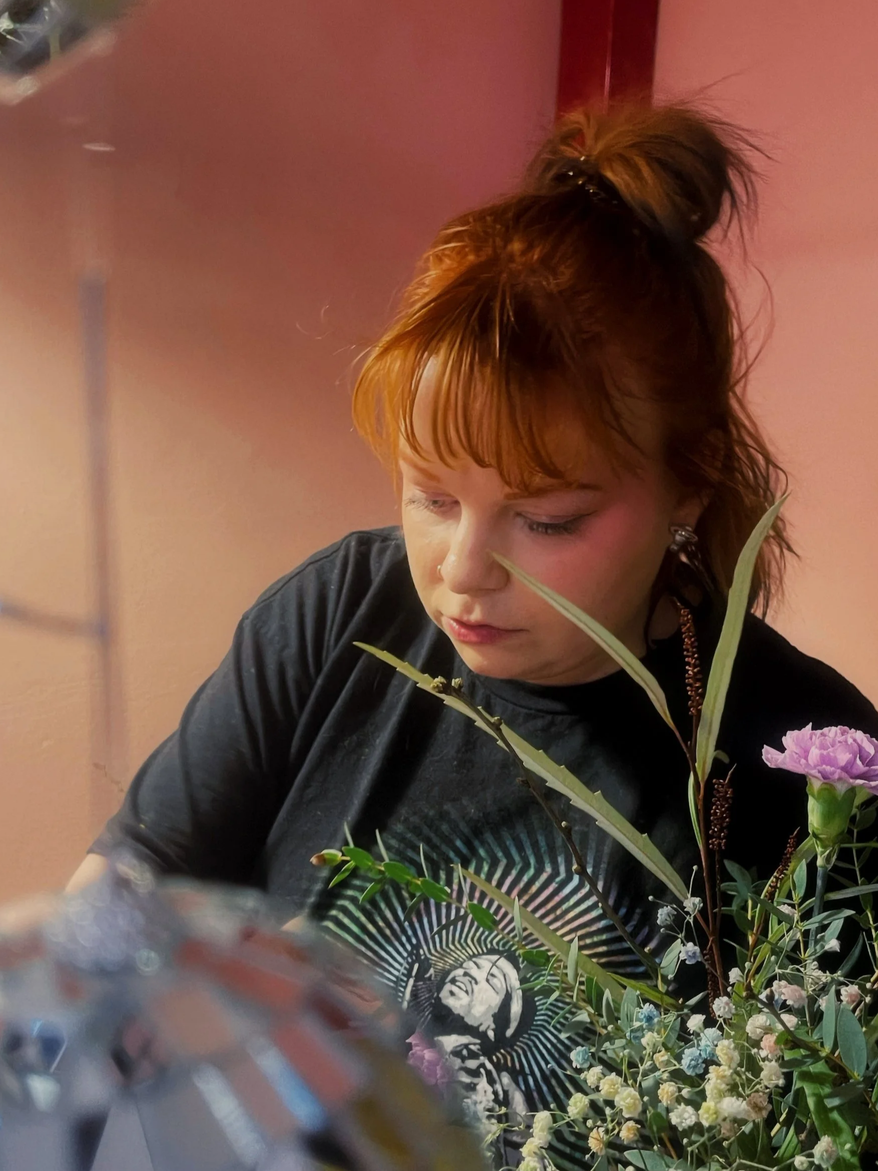 Florsti Janette sitomassa kukkakimppua, takana vaaleanpunainen seinä.
