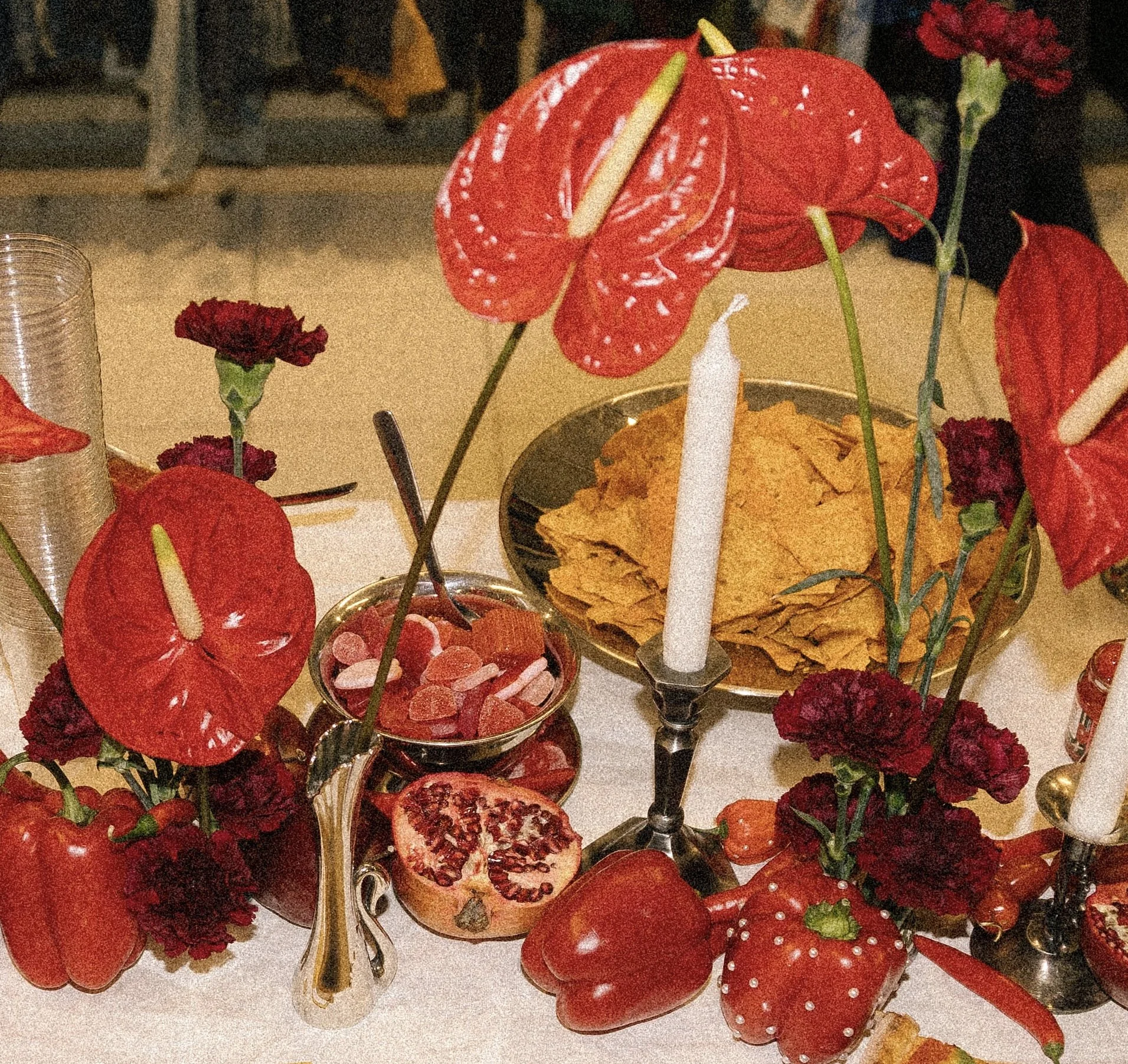 Juhlapöydässä on punaisia kukkia, pimentäliä, kynttilälyhtyjä, snackseja, paprika ja granaattiomena.