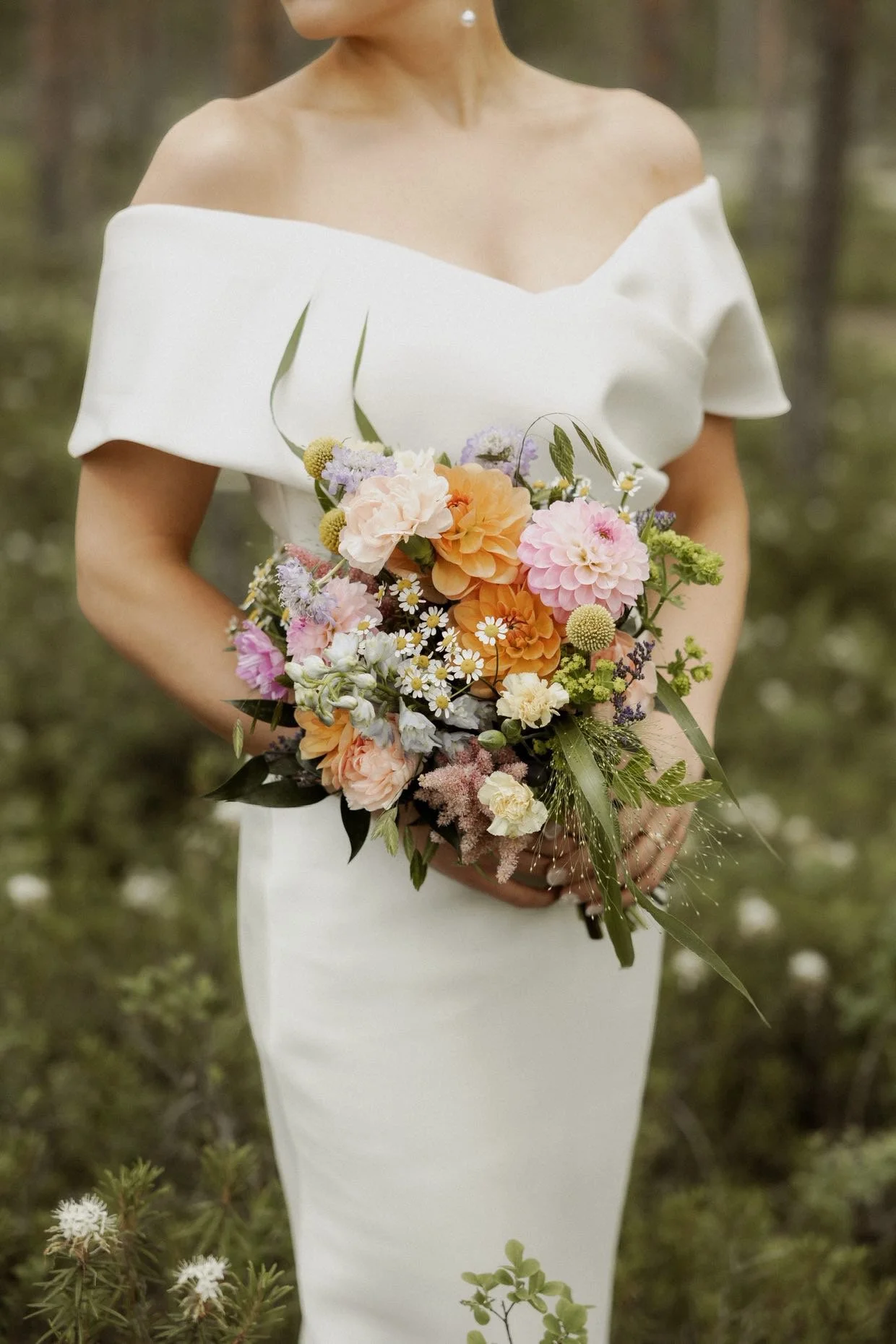 Morsian pitämässä värikästä kukkakimppua käsissään