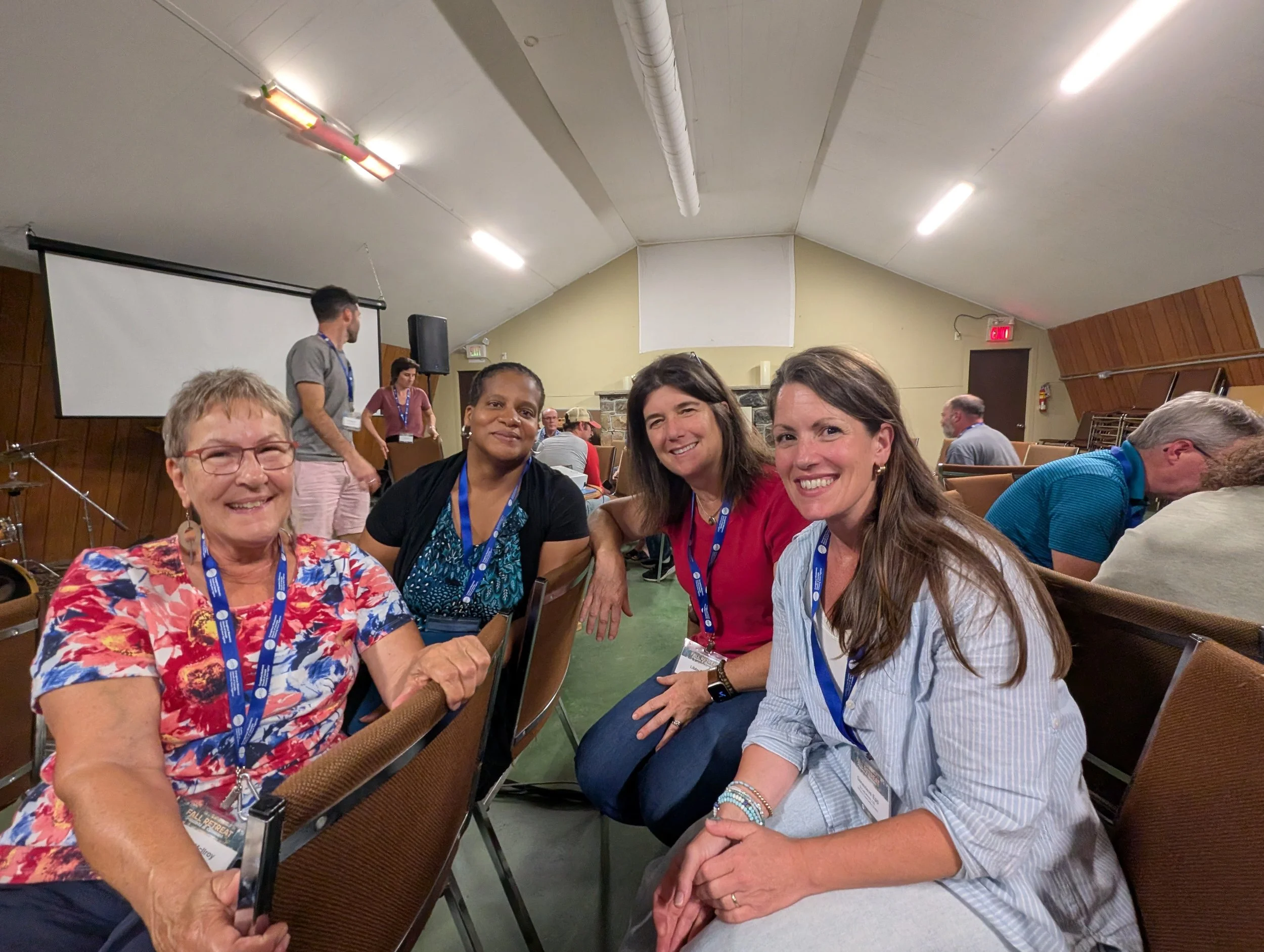 Four leaders at a fall retreat, seated together smiling at camera. Leaders are women.