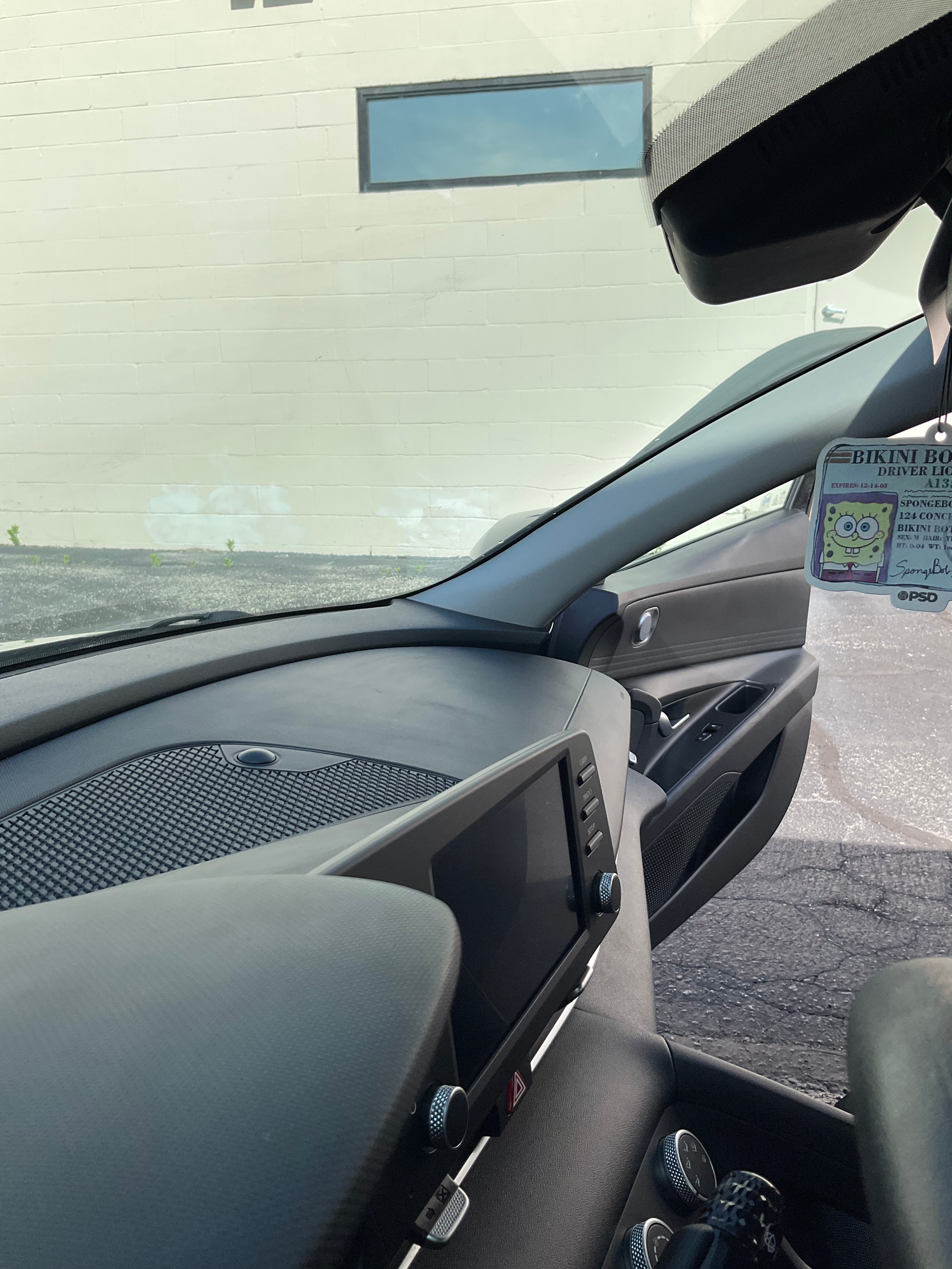 Car interior with dashboard, screen, and a novelty driver license hanging