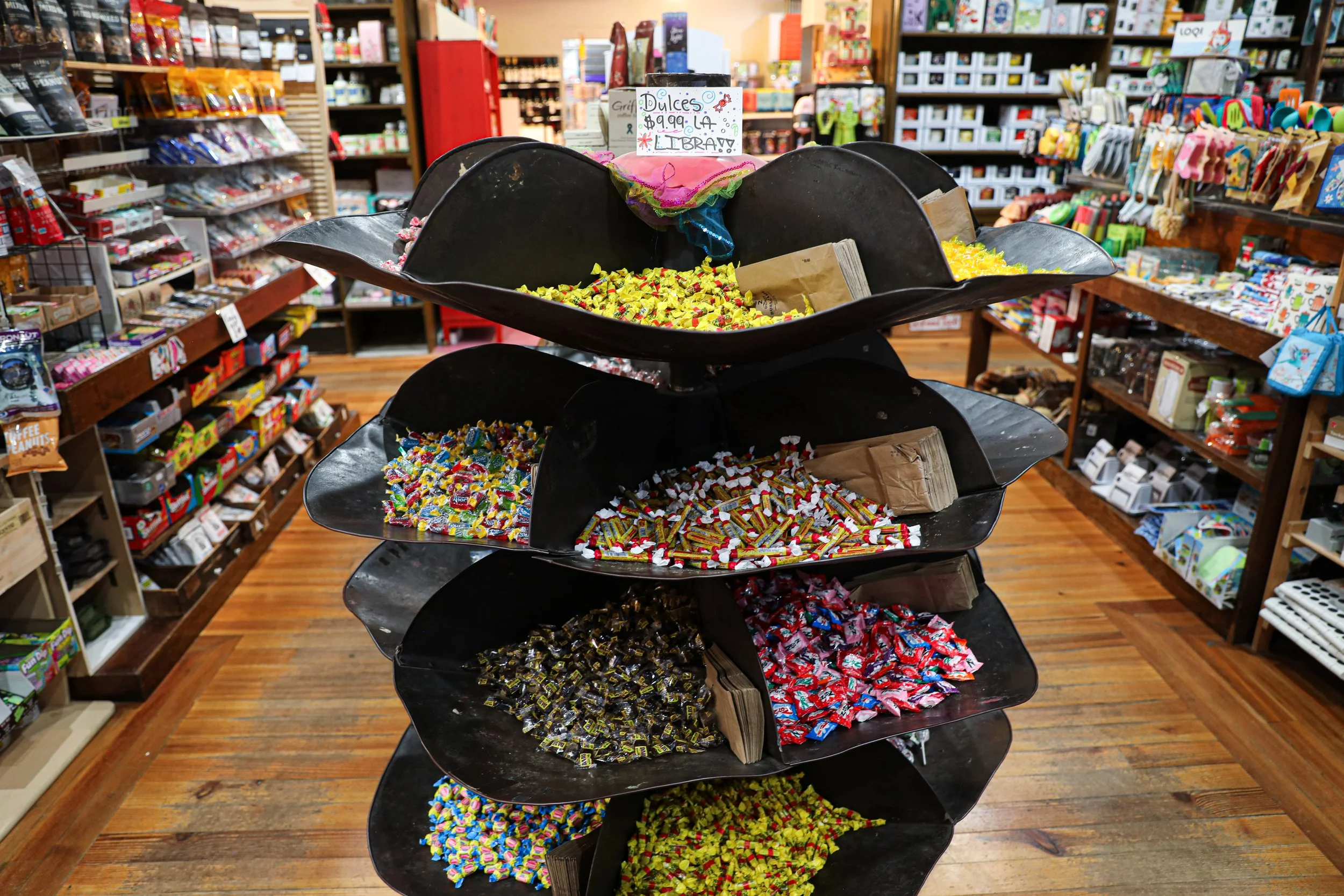 A Black Metal Multiple Tiered Candy Storage with brown paper bags to choose candy at Franklins General Store in Hyattsville