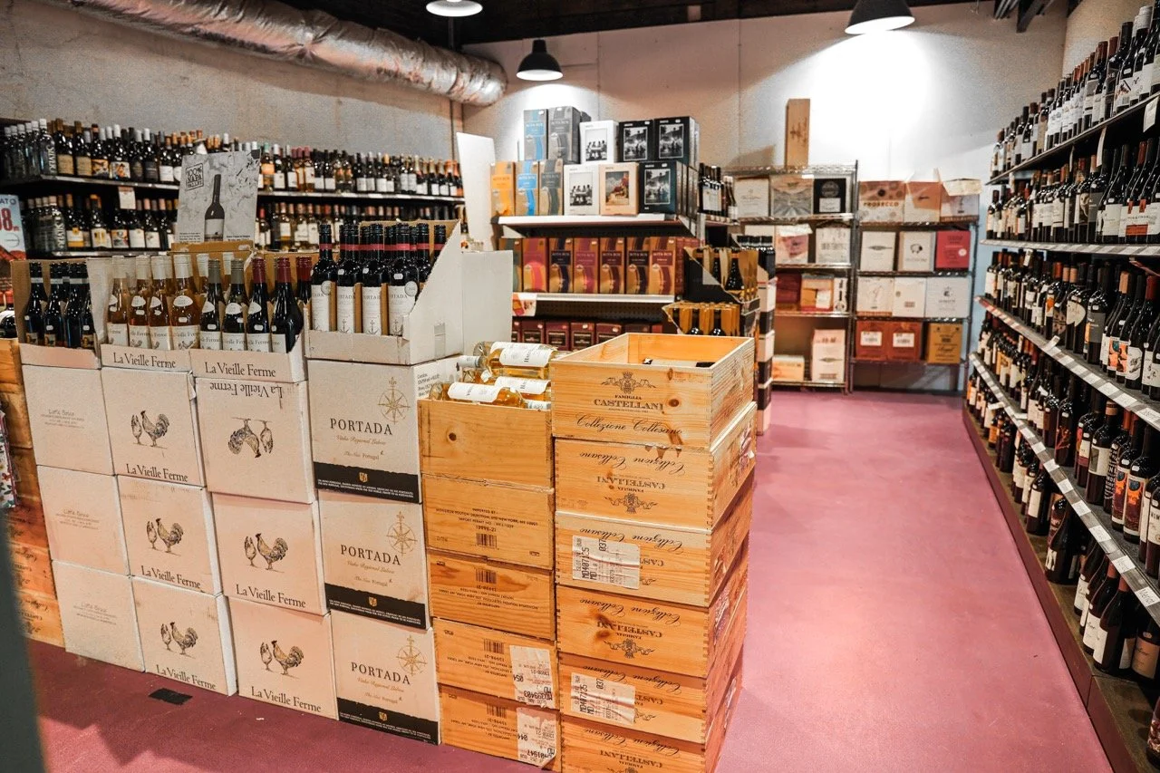Wooden and cardboard boxes stacked up and full of wine in a back room at Franklins General Store