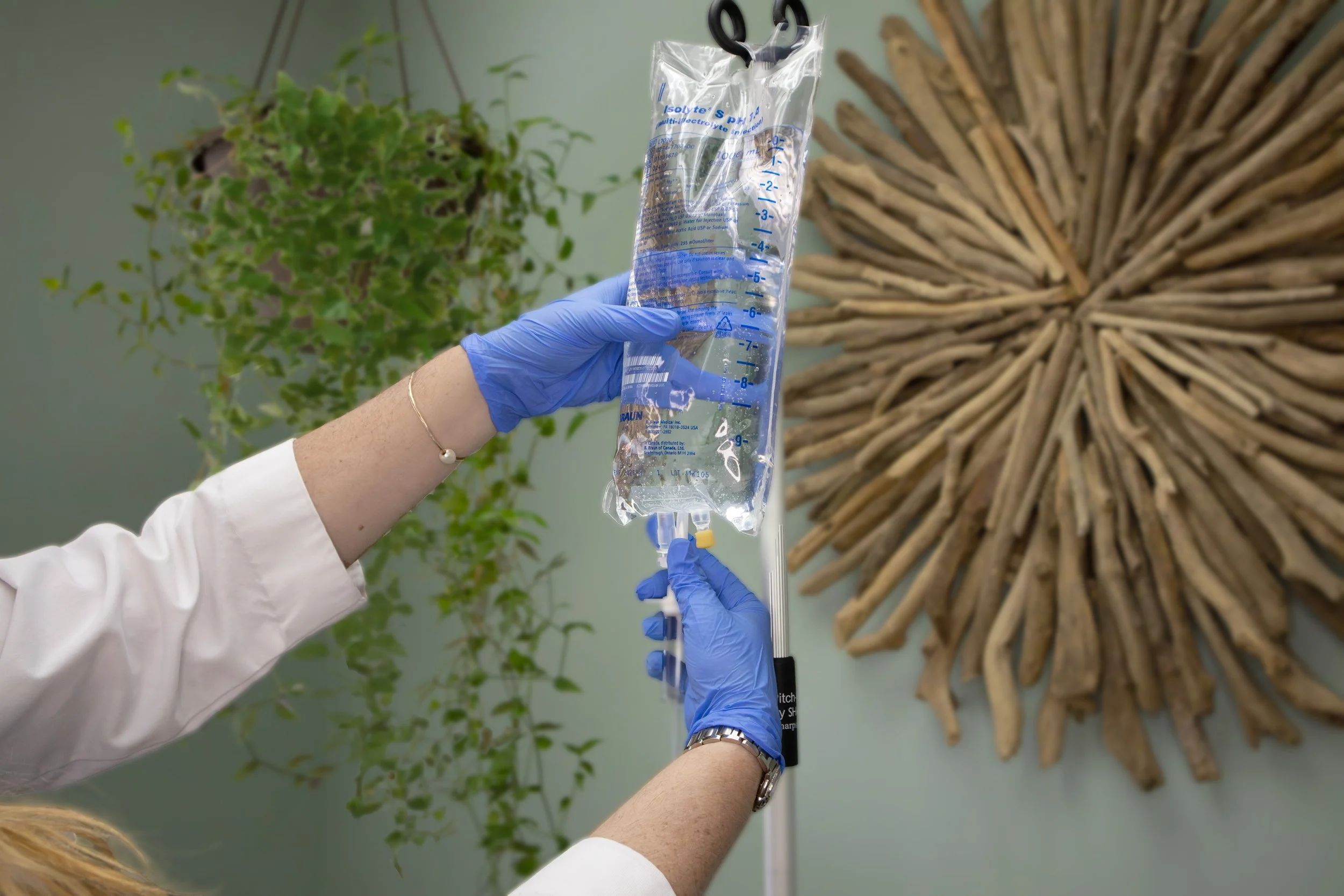 Person adjusting an IV bag with gloved hands
