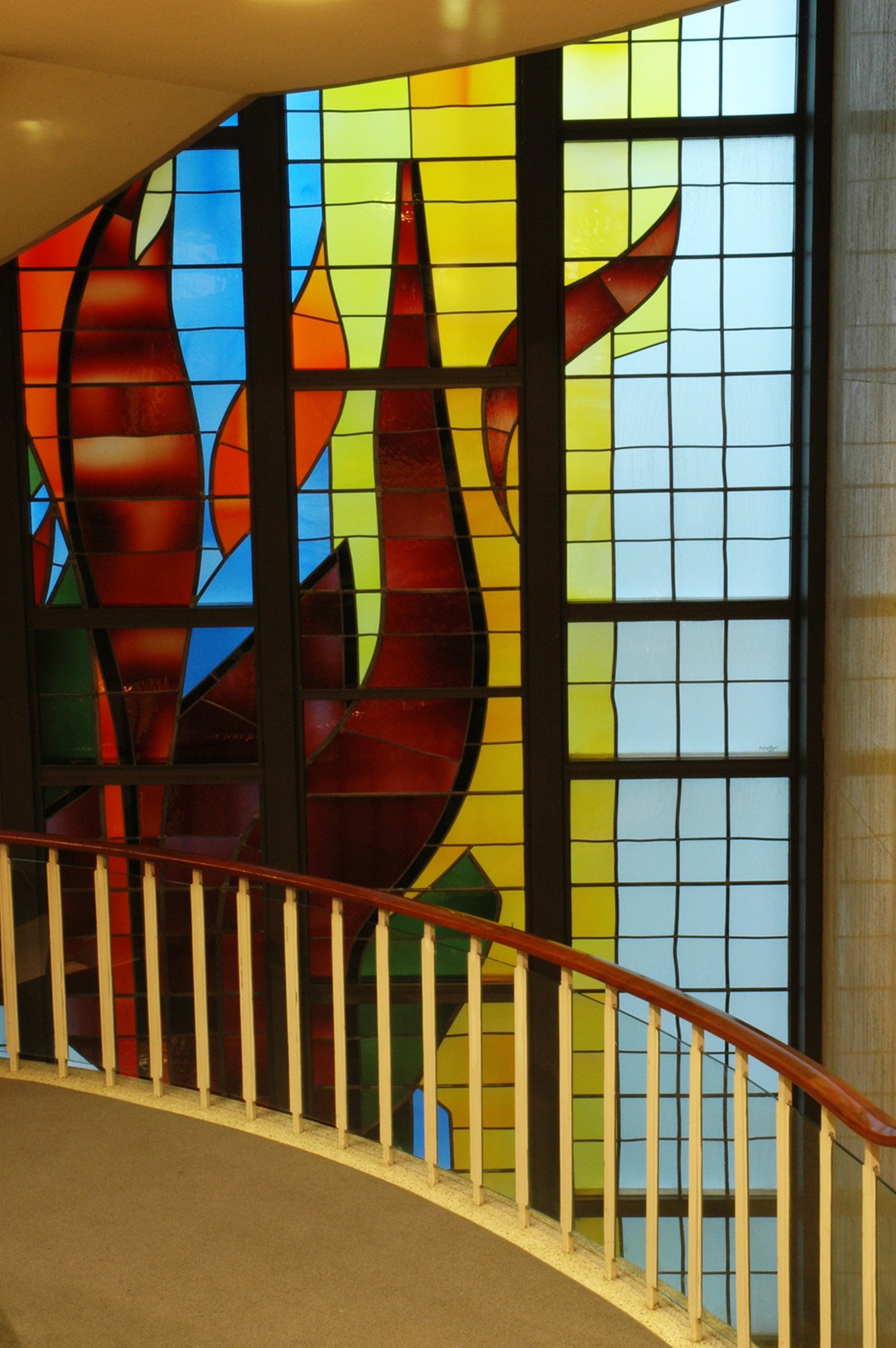 Colorful abstract stained glass window with a curved white railing in the foreground.