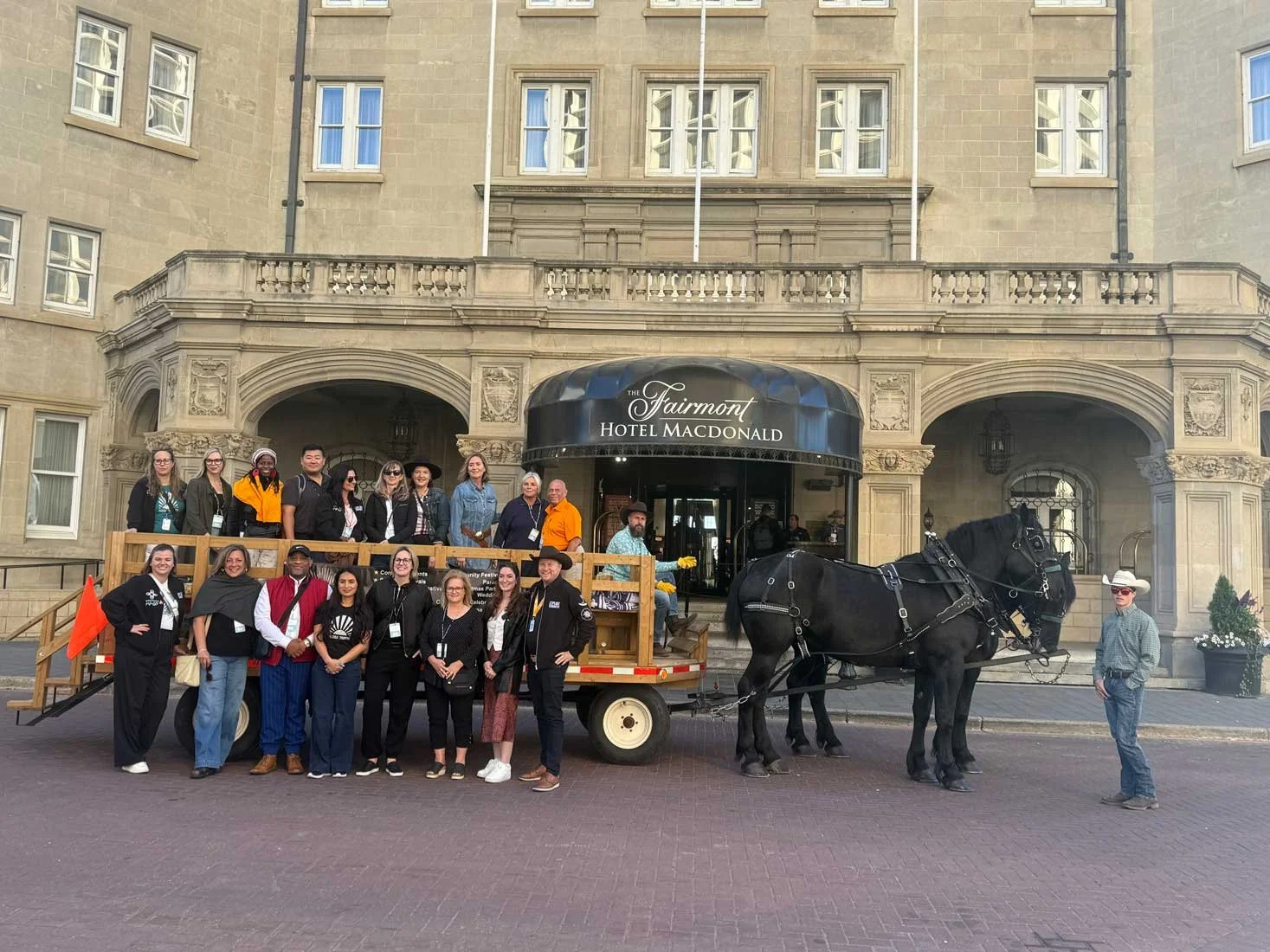 Group of people standing on a float with a horse and a driver in front of the Fairmont Hotel Macdonald building.