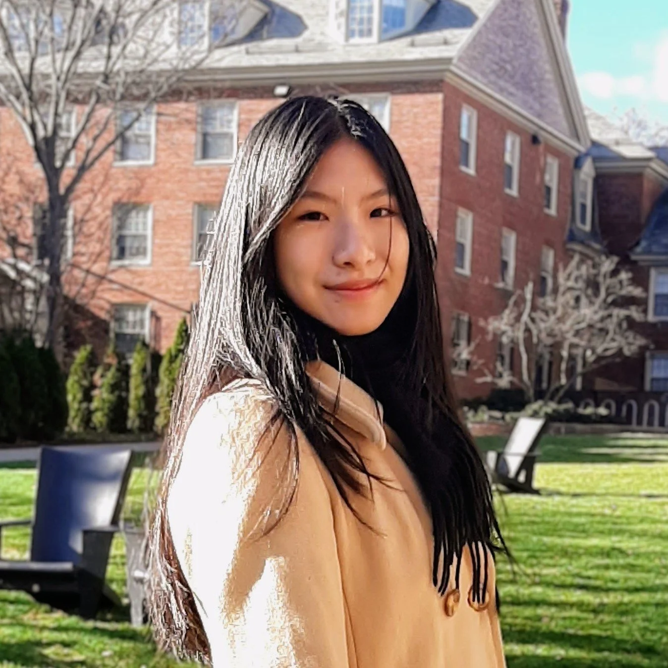 An Asian American woman with medium-long black hair is shown from he torso up, wearing a white sweater.