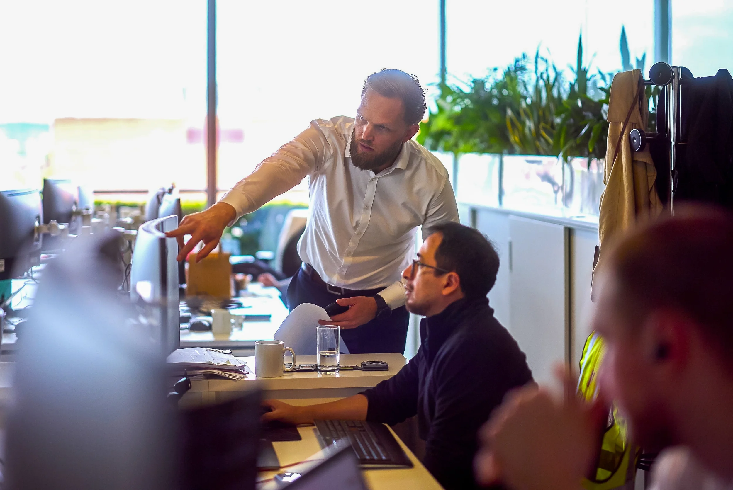 Two Bryden Wood consultants review design work at a desktop screen in the London studio. Bryden Wood's strategic consultancy combines analytics, simulation and deep sector expertise to help clients make better investment decisions.