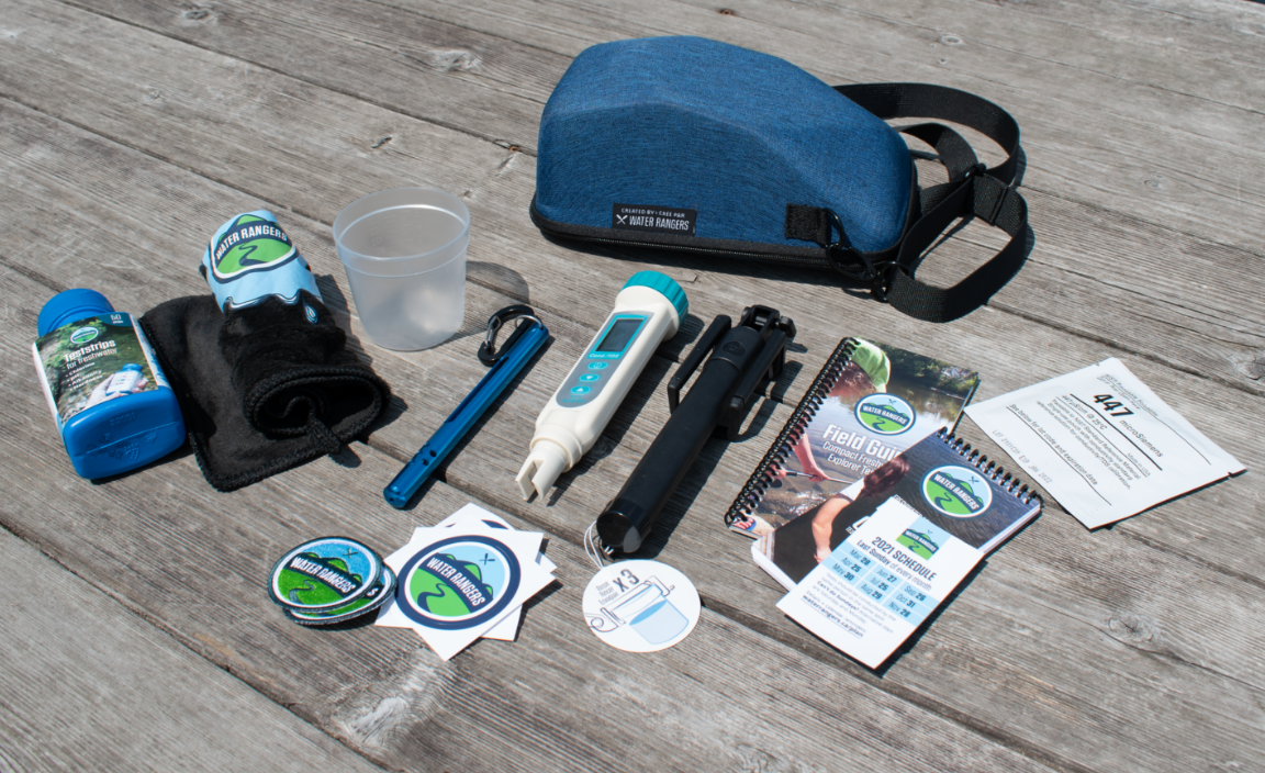 Water quality testing kit with testing strips, digital tester, water sample containers, stickers, a notebook, and a bag on a wooden surface.