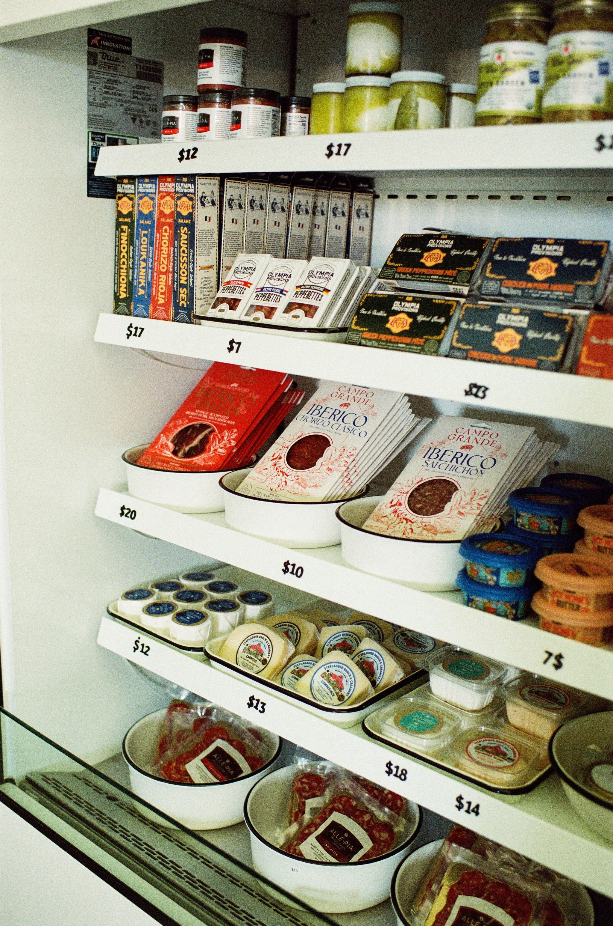 Shelves with various deli meats and cheeses in a grocery store, labeled with prices.