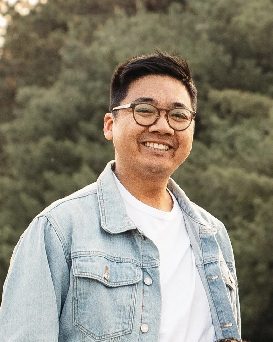 Iven Chung, registered psychotherapist in Kitchener-Waterloo, smiling outdoors in a denim jacket, conveying a warm and approachable demeanour.
