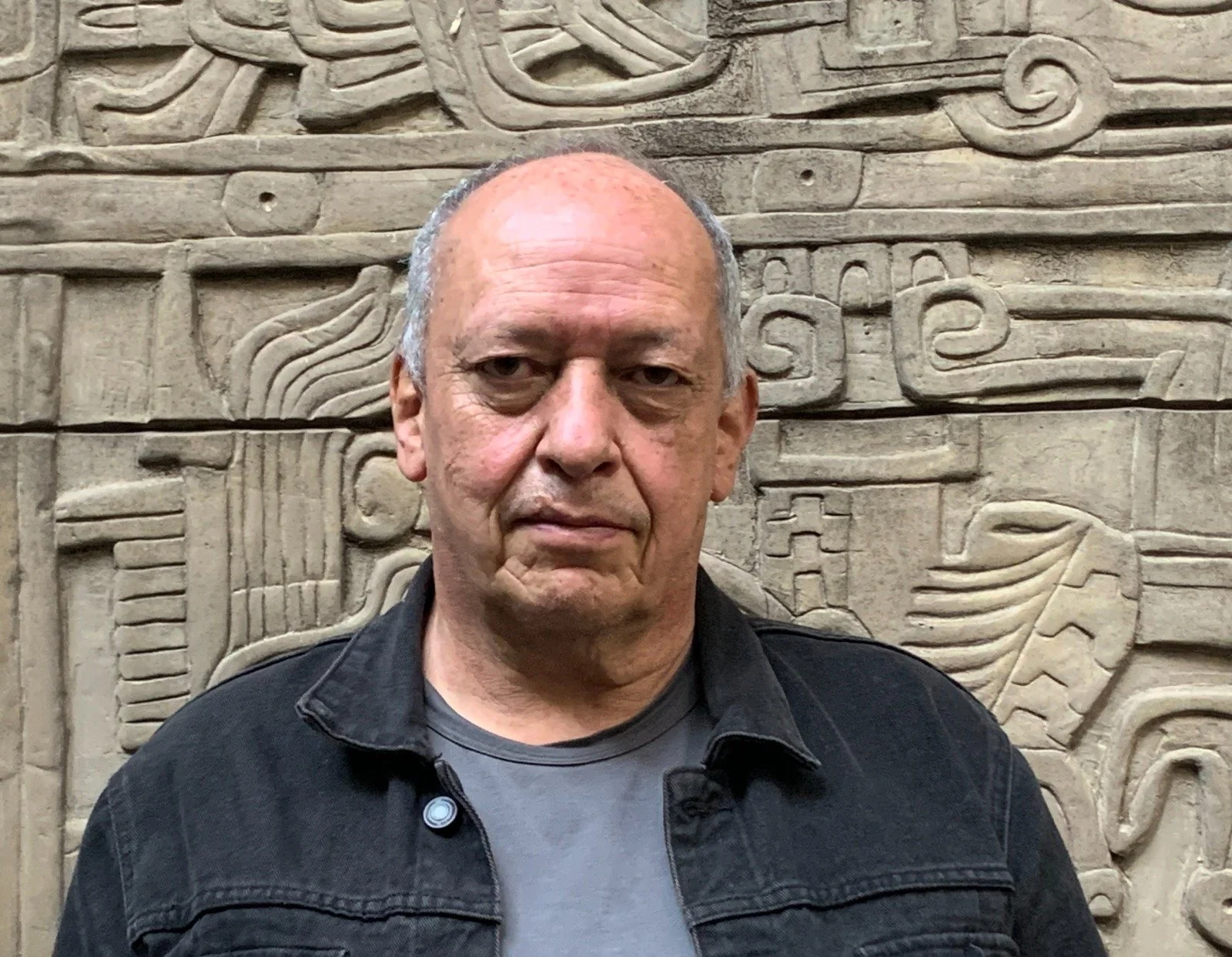 Man in front of stone wall with carvings