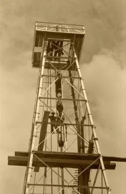 A person climbing a metal construction tower with a platform at the top.