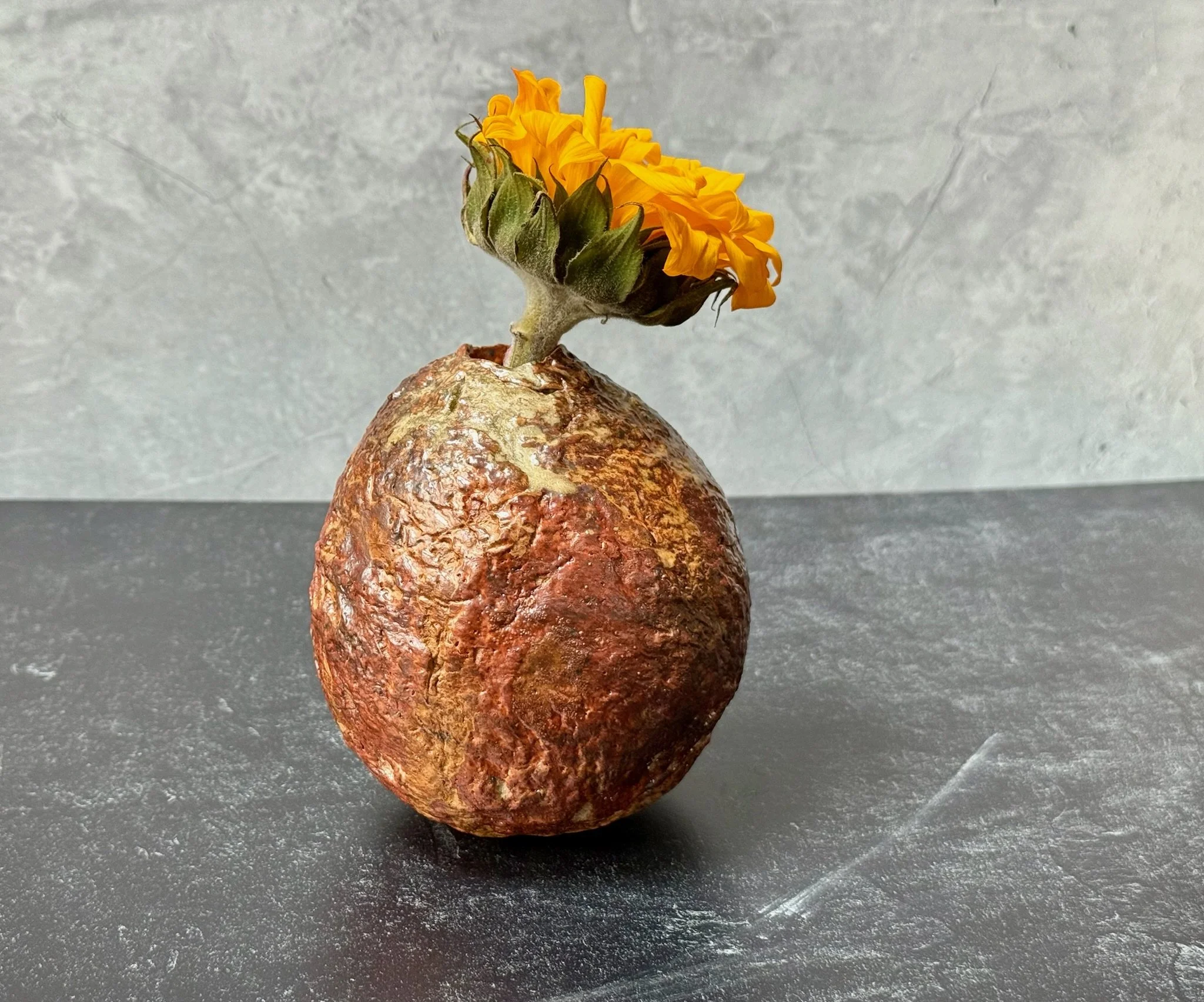 Small red stoneware moon vase with gold shino and ash-kissed texture.