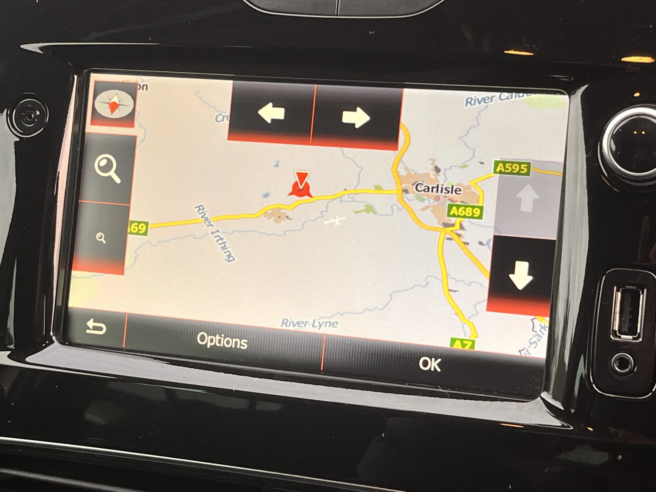 Car GPS navigation screen showing a map of Carlisle and surrounding roads with directions options.