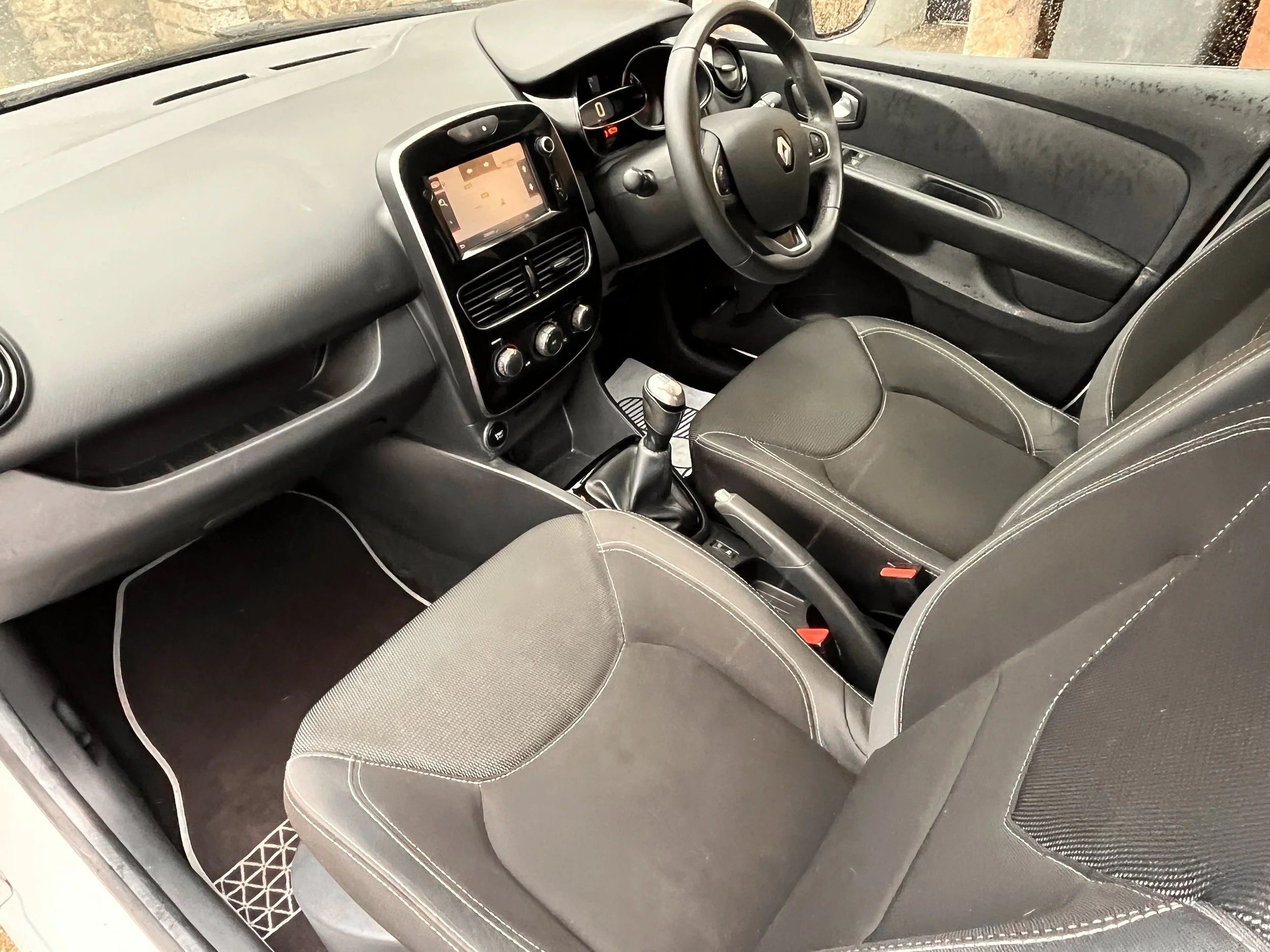 Interior of a Renault car showing dashboard, steering wheel, gear shift, and front seats.