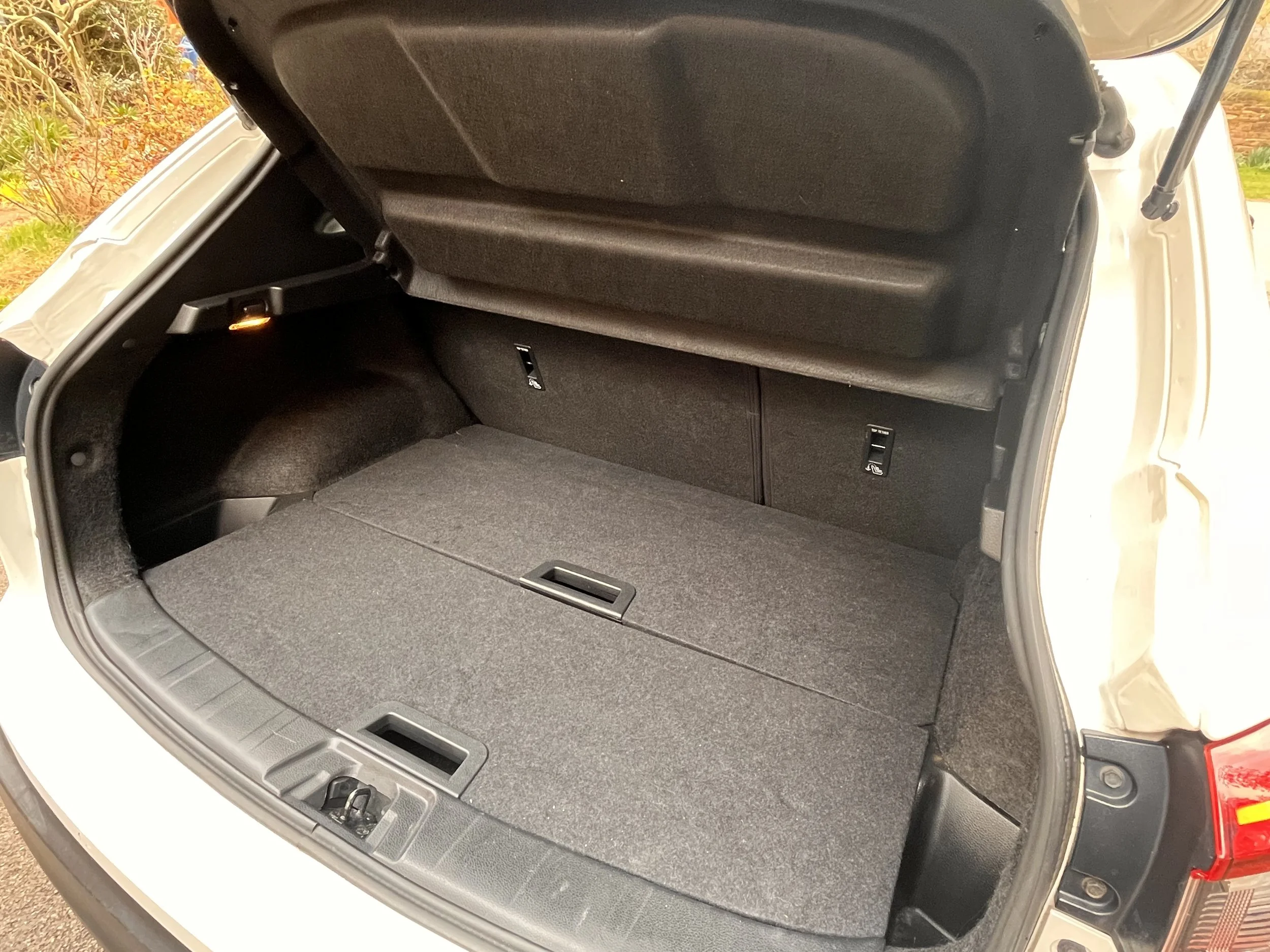 Empty car trunk with folded rear seats and black interior lining.