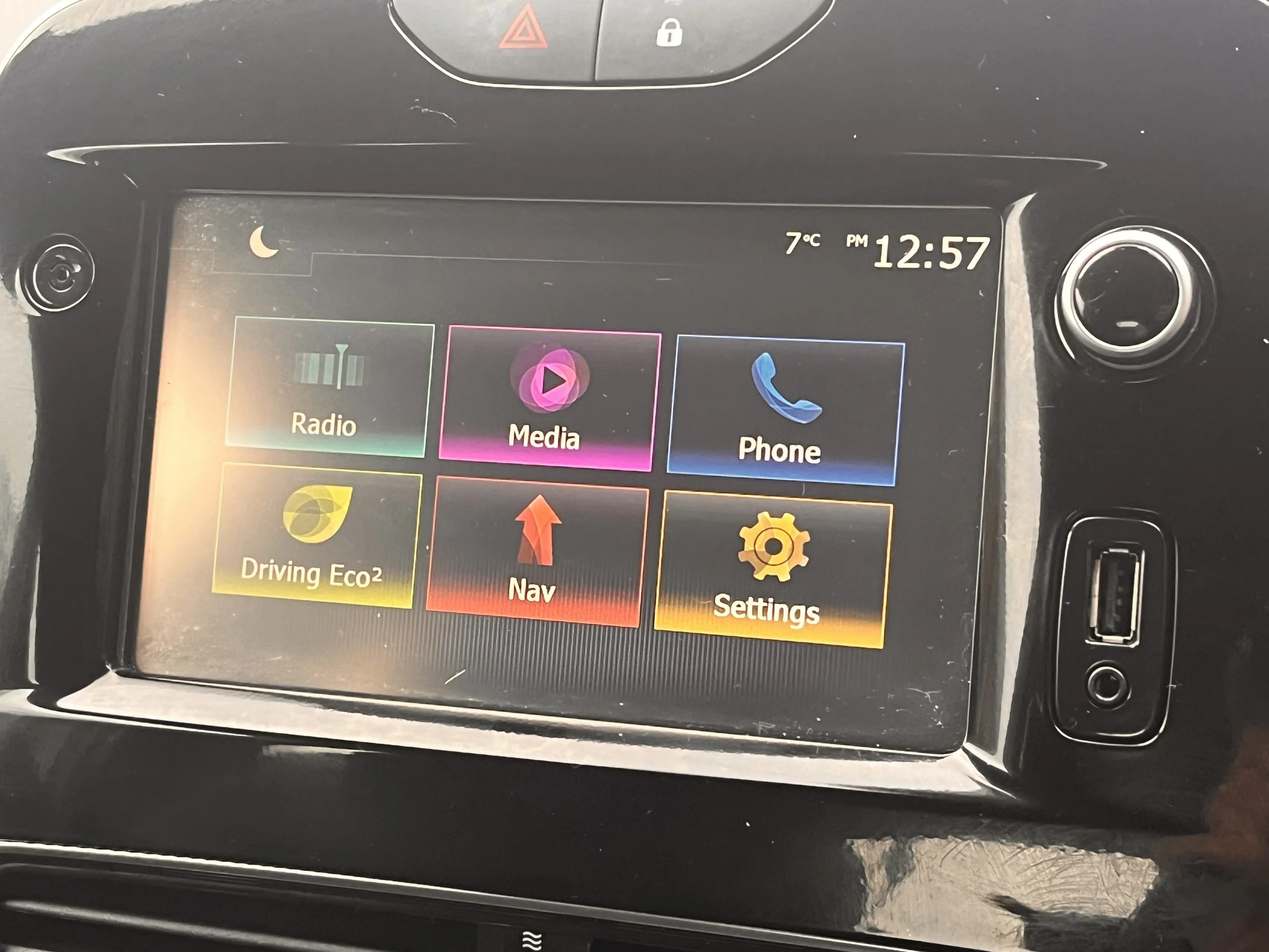 Car dashboard with touchscreen display showing options for Radio, Media, Phone, Driving Eco, Nav, and Settings. The time is 12:57 PM and the temperature is 7°C.