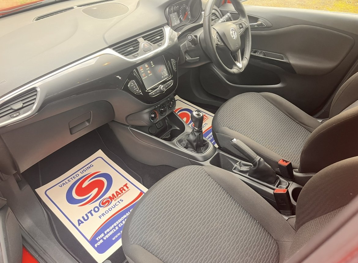 Interior of a car showing the dashboard, steering wheel, gear shift, and front seats with floor mats from Auto Smart.