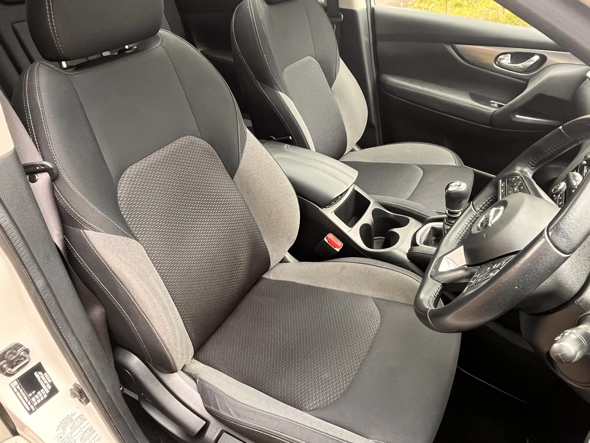 Interior of a vehicle showing the driver's and passenger's seats, center console, gear shift, and part of the steering wheel.